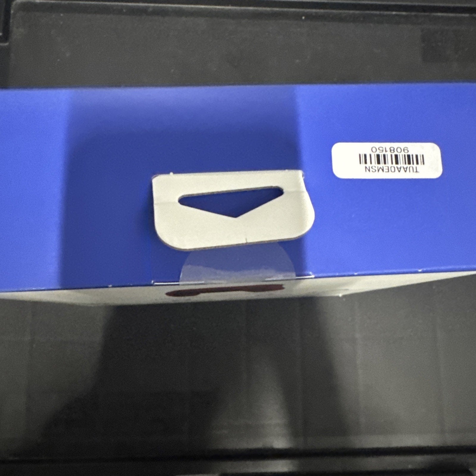 Close-up of box edge with white triangular tab and barcode sticker on blue packaging surface