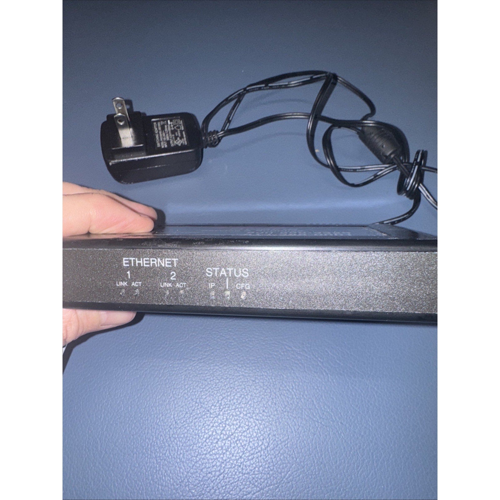 Print Counter DEX Imaging Emerge Print Management device showing Ethernet ports and power adapter held against blue background