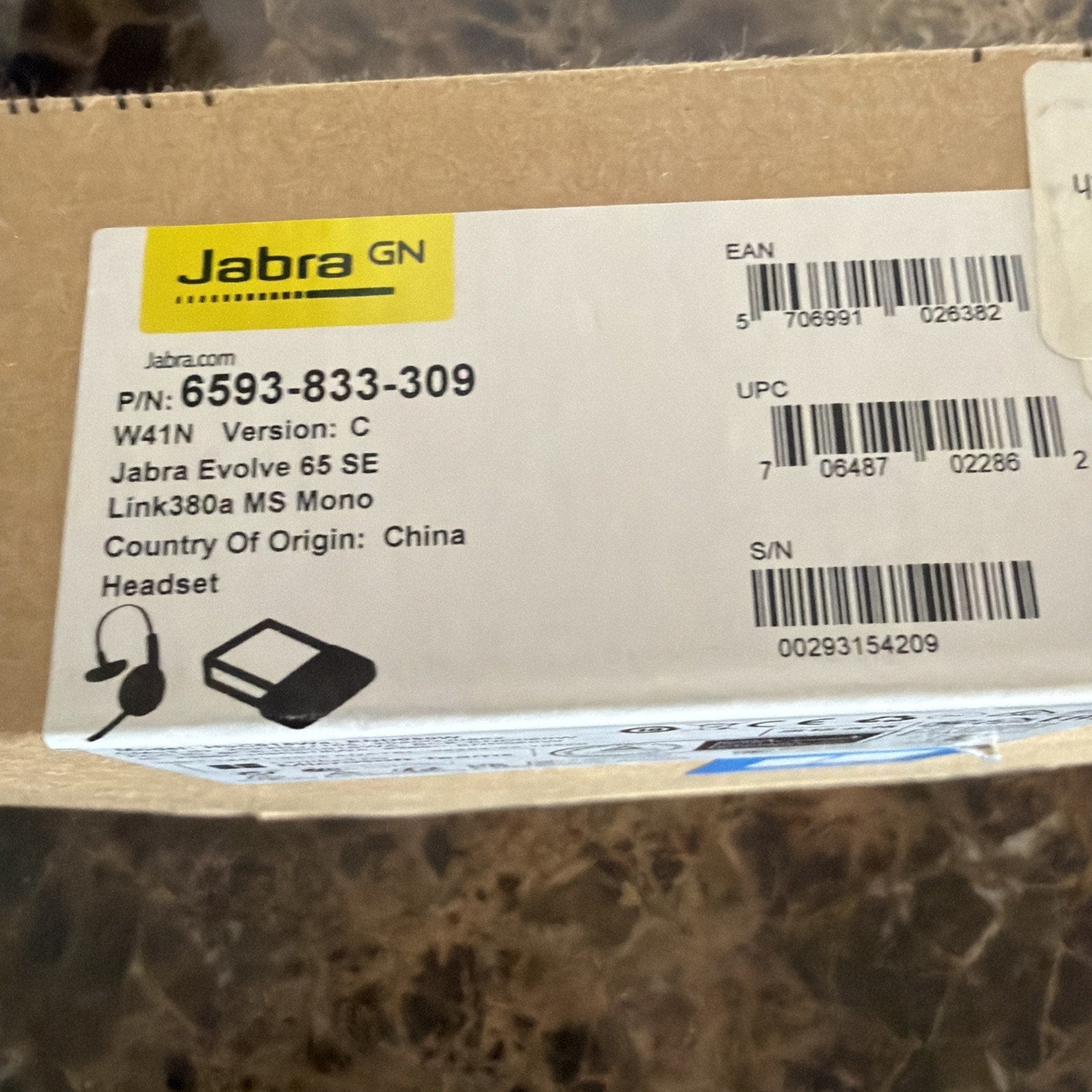 White product label on a brown cardboard box showing Jabra branding, part numbers, barcodes, and information for a Jabra Evolve 65 SE Link380a MS Mono headset made in China.