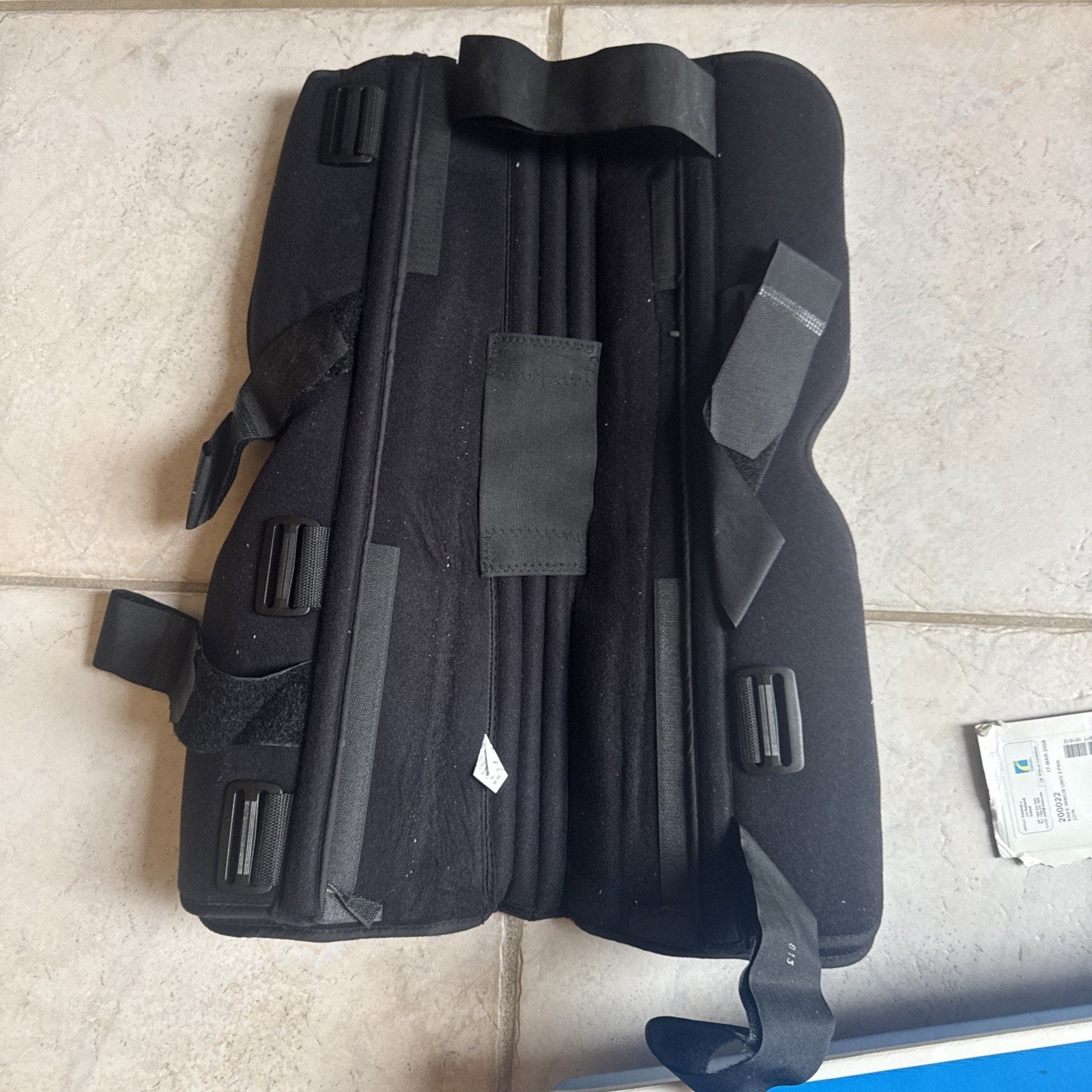 Össur Knee Immobilizer Universal 3-Panel 22 inch model 200022 black knee brace with adjustable straps laid flat on tile floor