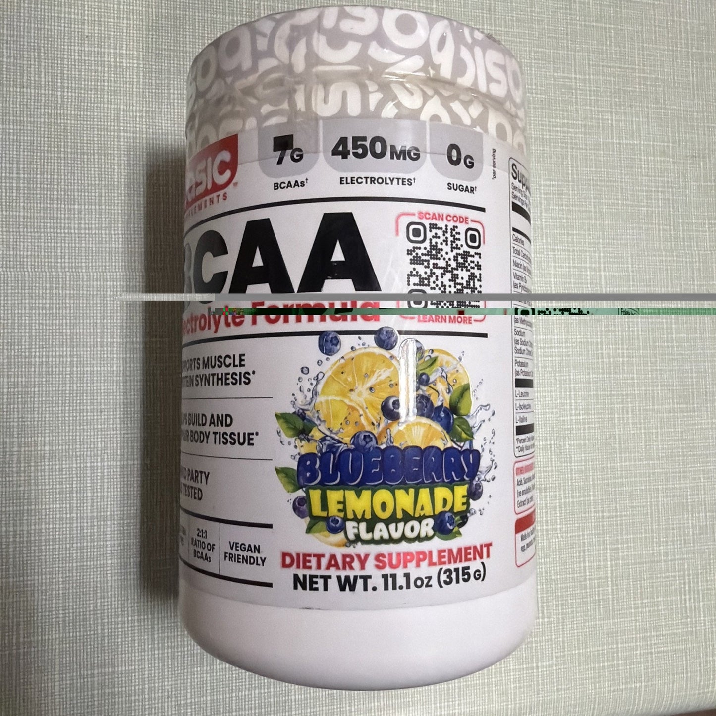 White container of a blueberry lemonade flavored dietary supplement with 7g BCAAs, 450mg electrolytes, and zero sugar, featuring colorful fruit graphics and vegan-friendly labeling.