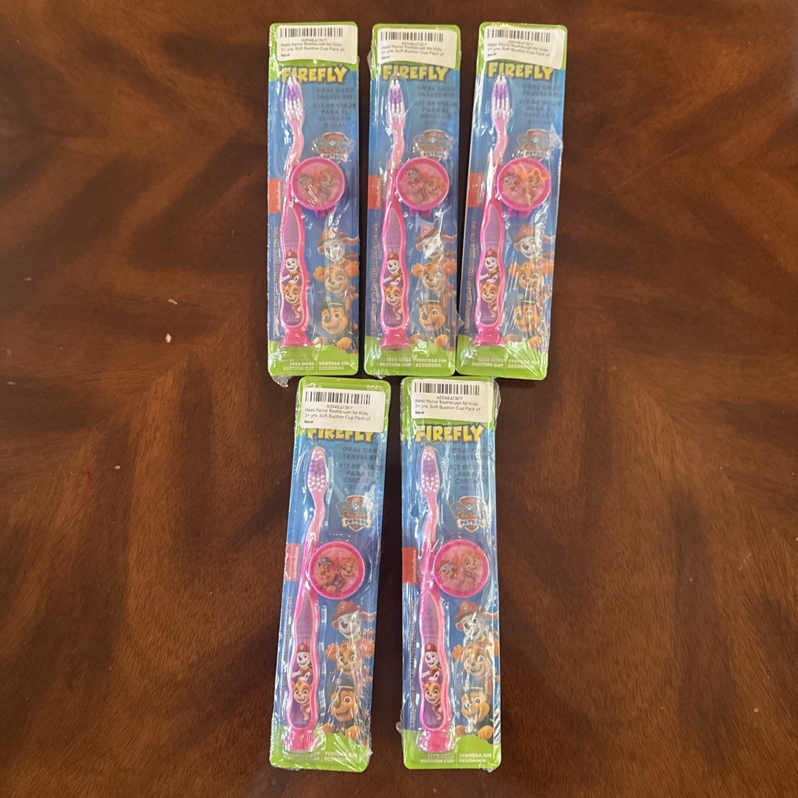 10-pack Firefly Nickelodeon Paw Patrol kids soft manual toothbrushes with caps in original packaging on wooden surface