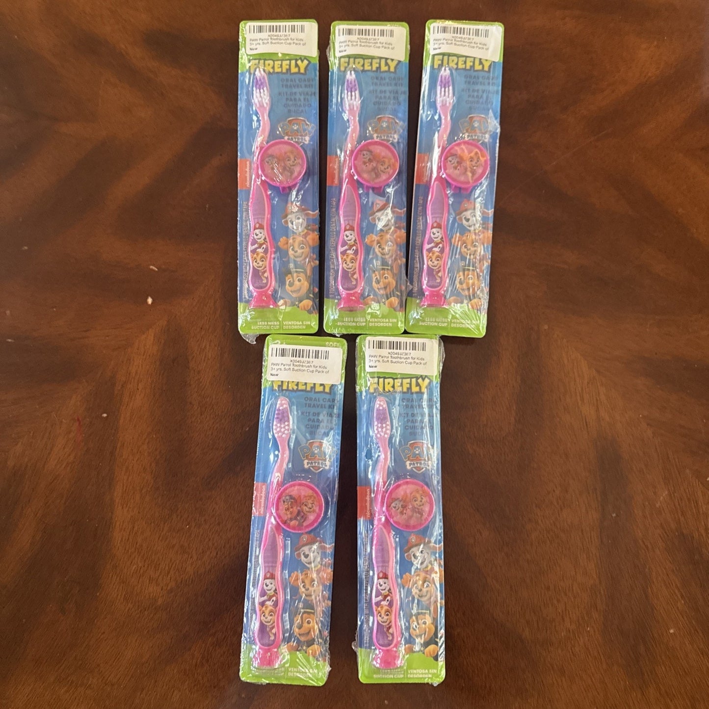 10-pack Firefly Nickelodeon Paw Patrol kids soft manual toothbrushes with caps in original packaging on wooden surface