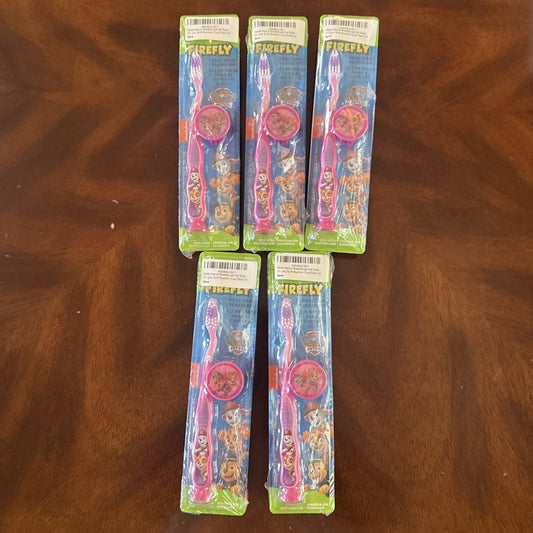 10-pack Firefly Nickelodeon Paw Patrol kids soft manual toothbrushes with caps in original packaging on wooden surface