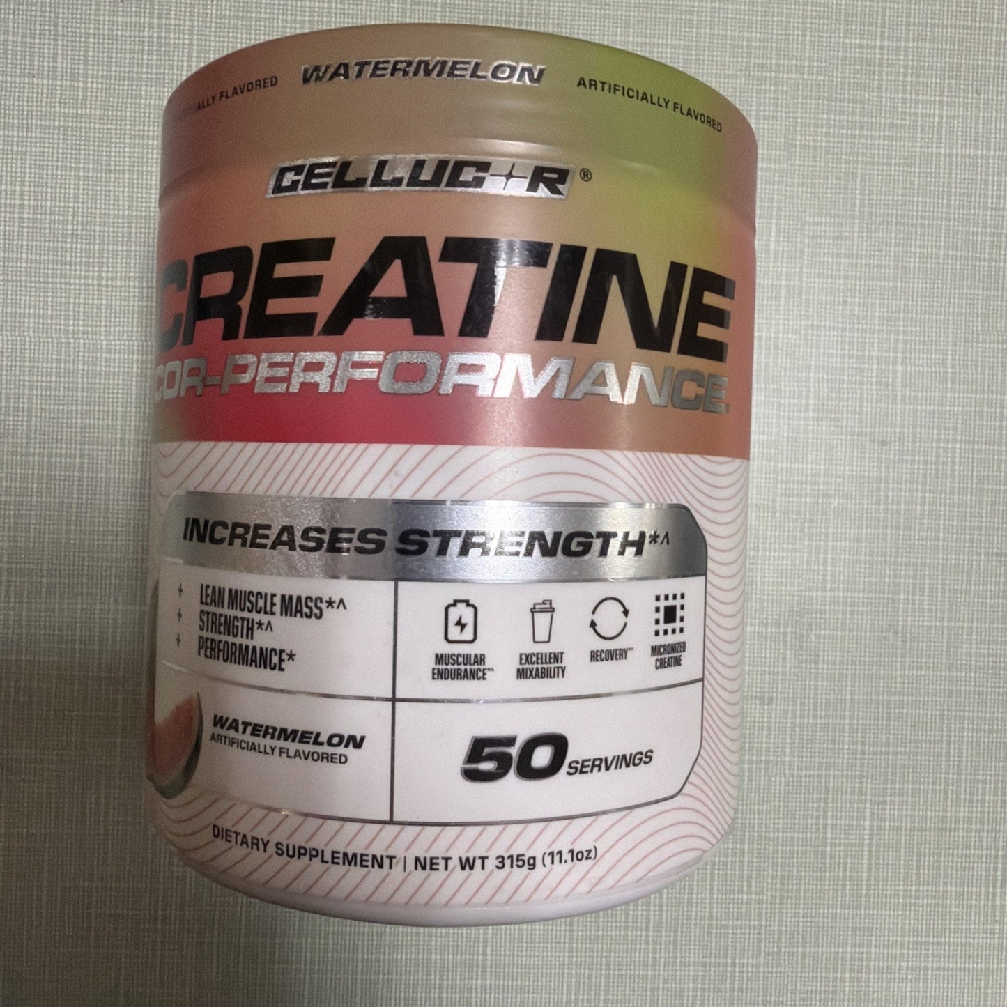 Container of watermelon-flavored creatine supplement with label highlighting strength increase, lean muscle support, 50 servings, and benefits like muscular endurance and recovery.