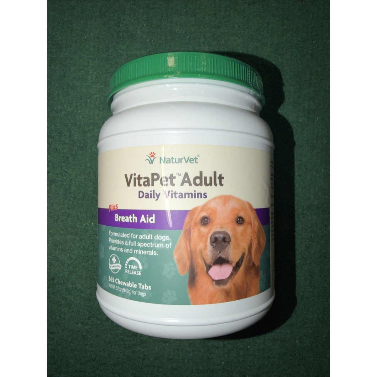 White plastic container with a green lid labeled NaturVet VitaPet Adult Daily Vitamins plus Breath Aid, featuring an image of a golden retriever and text about chewable tabs for adult dogs.