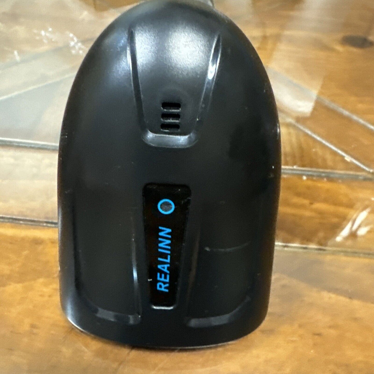 Black Realinn RL6200 wireless barcode scanner standing upright on wooden surface with logo visible on front panel