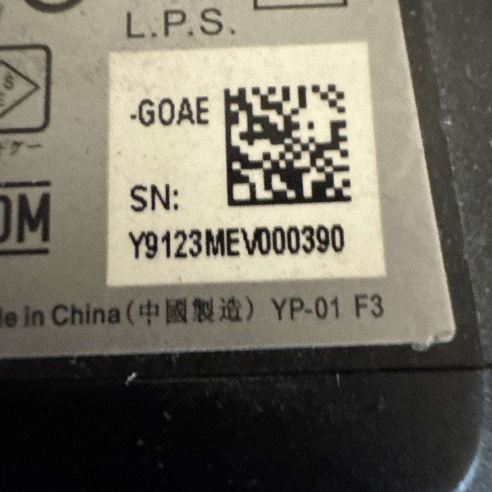 Close-up of power supply label for ADT camera model RC8025 showing serial number and QR code on beige sticker
