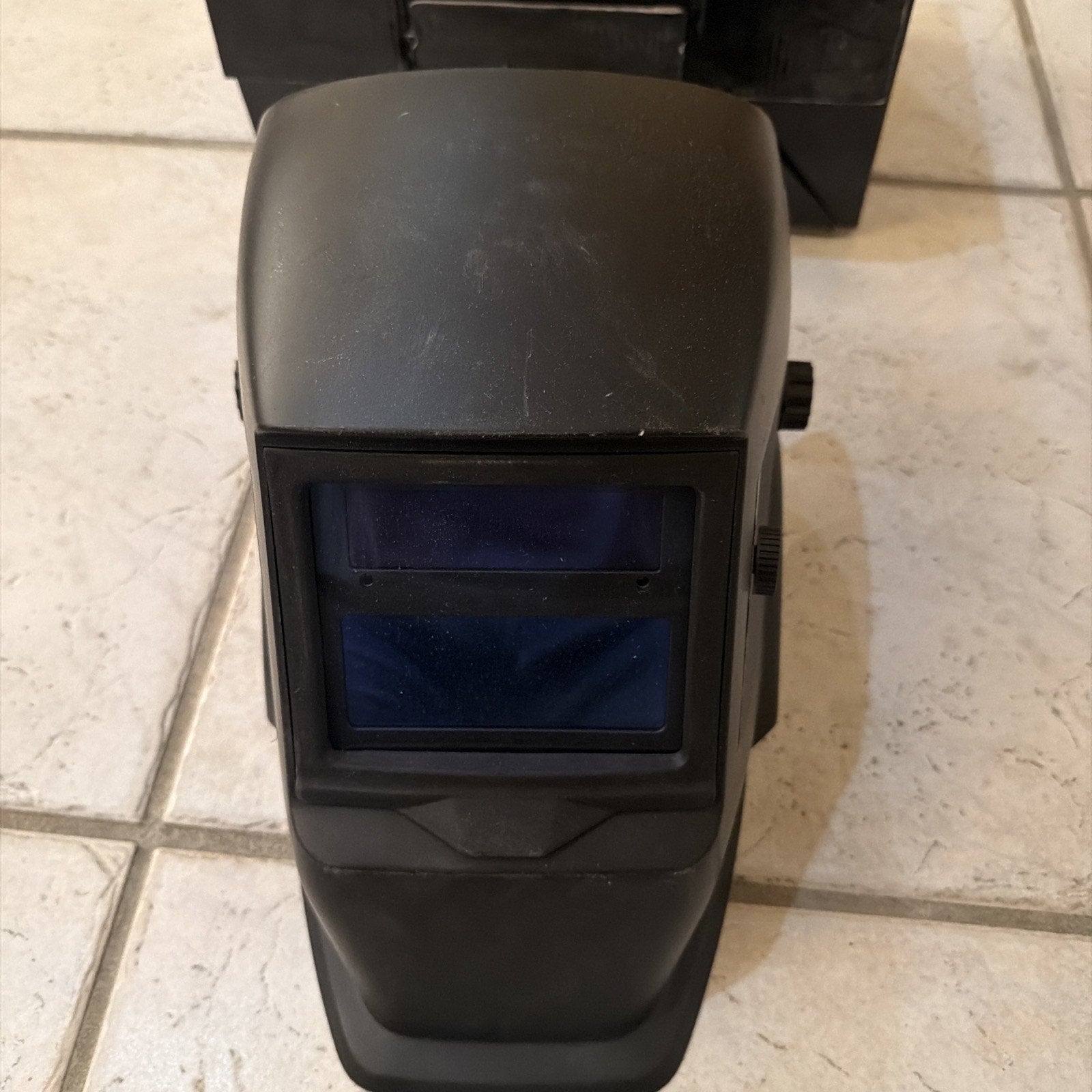 Chicago Electric auto-darkening welding helmet in black with adjustable shade and plastic protective lens shown on tile floor