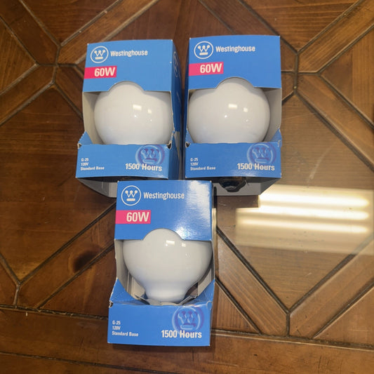 Three Westinghouse 60 Watt G25 vintage frosted globe light bulbs in blue and white packaging on wooden floor
