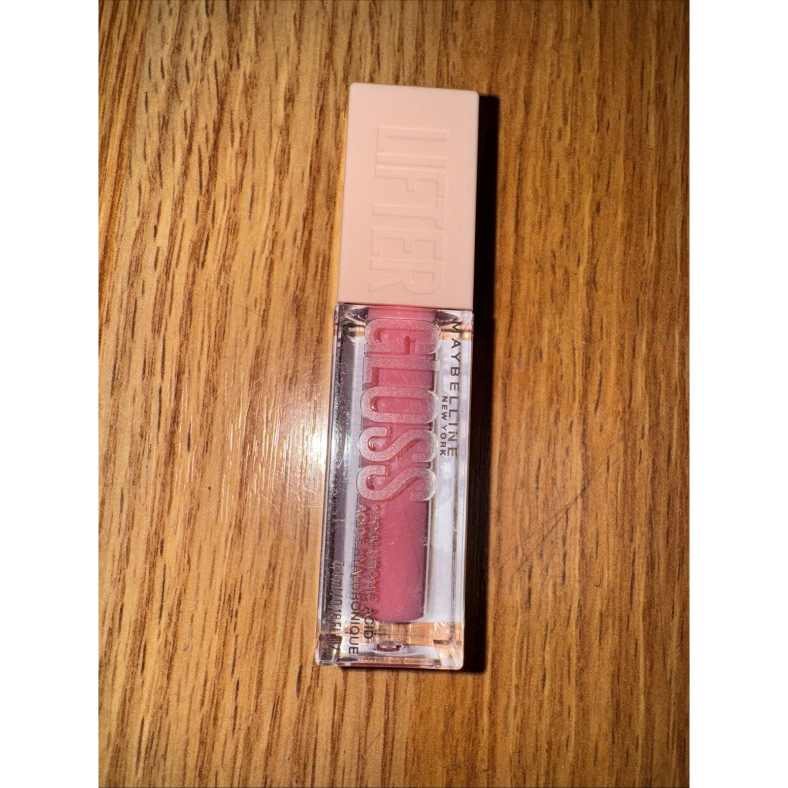 Maybelline New York Lifter Lip Gloss with Hyaluronic Acid in Sheer Light Pink shade on wooden surface