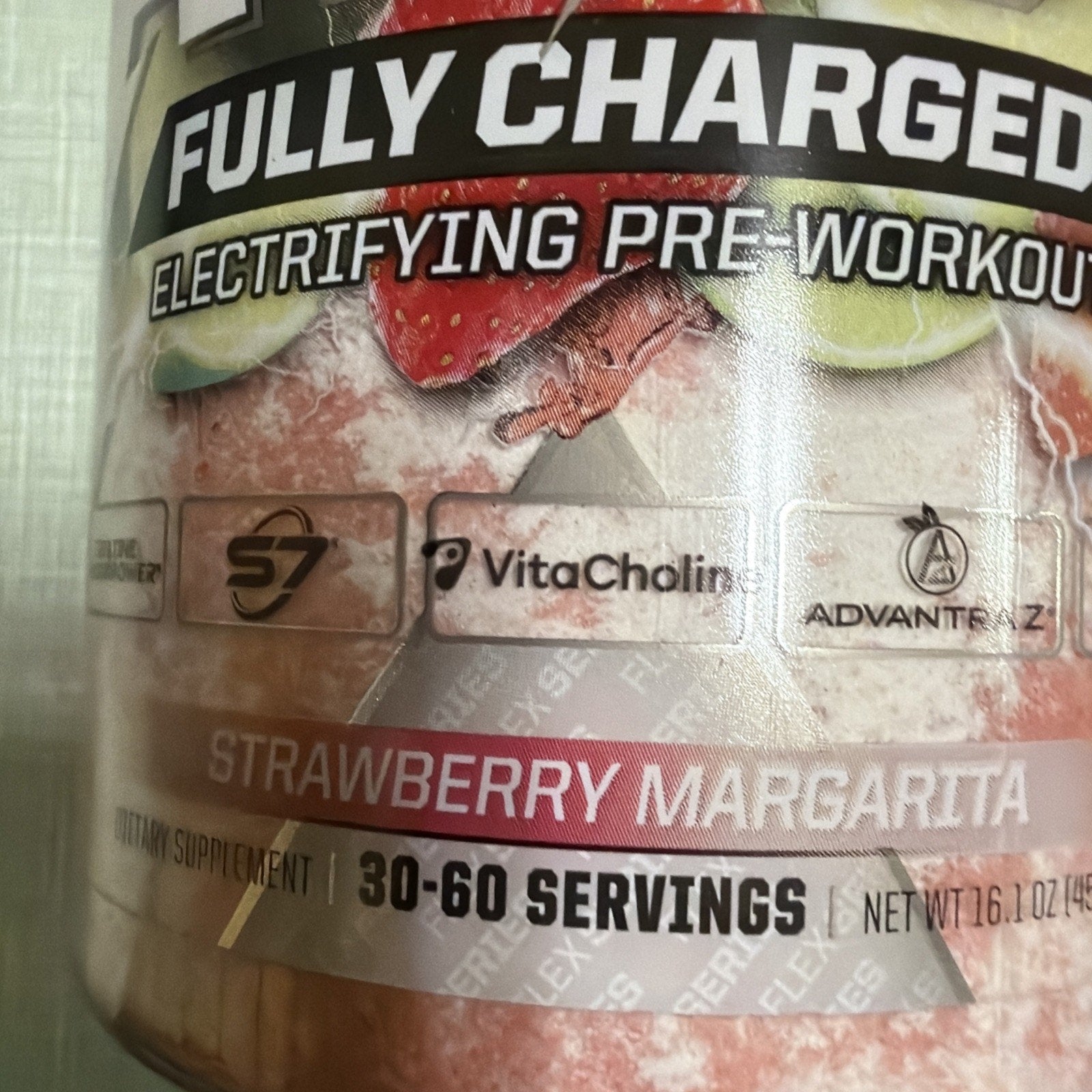 Close-up of a pre-workout supplement label highlighting the "Fully Charged Electrifying Pre-Workout" in strawberry margarita flavor with 30 to 60 servings and ingredient logos including S7, VitaCholine, and AdvantEdge.