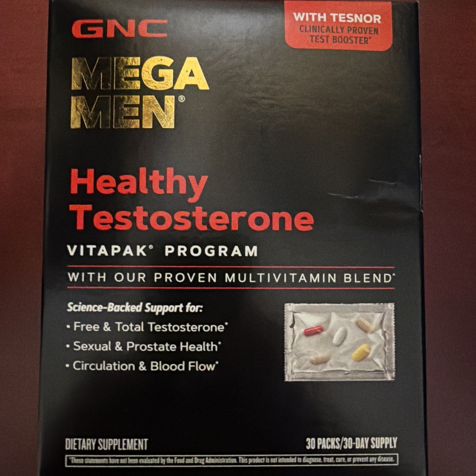 Box packaging for a dietary supplement featuring multivitamin pills in a blister pack, highlighting support for testosterone, sexual health, and circulation, with bold red and gold text on a black background.