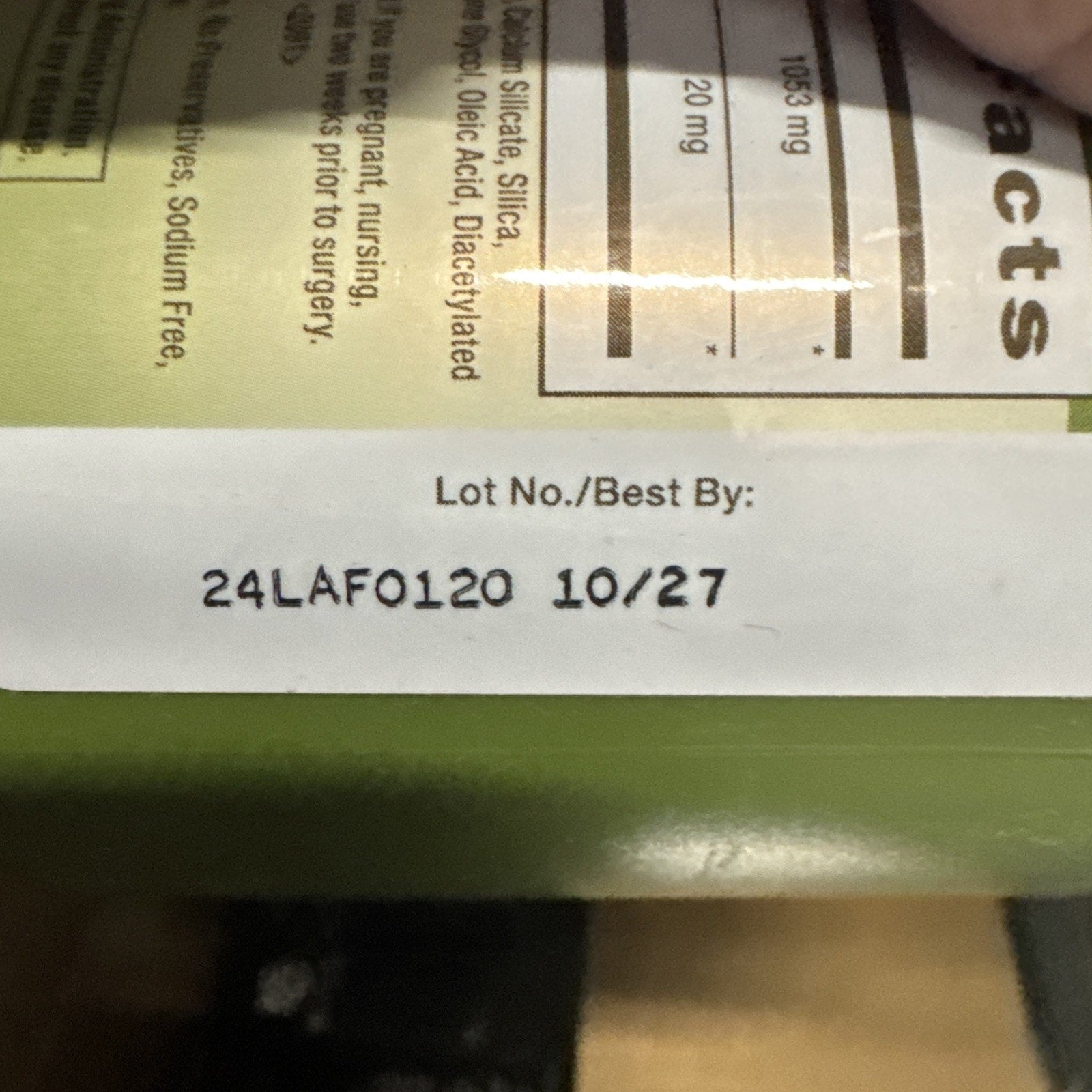 Close-up of a product package showing a printed lot number "24LAF0120" and best-by date "10/27" on a white label strip against a green background.