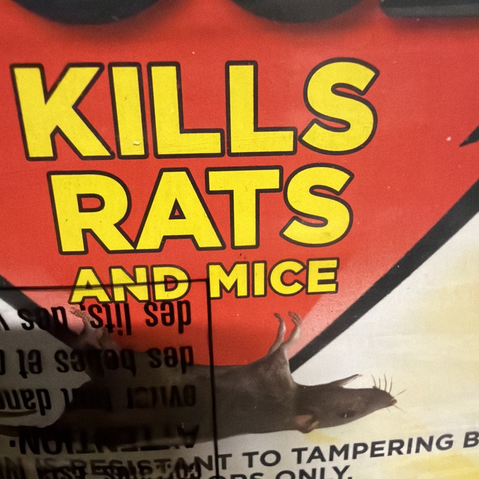 Bright yellow text on a red background stating "KILLS RATS AND MICE" with a close-up of a dead rat positioned below the text and partially visible warning text beneath.