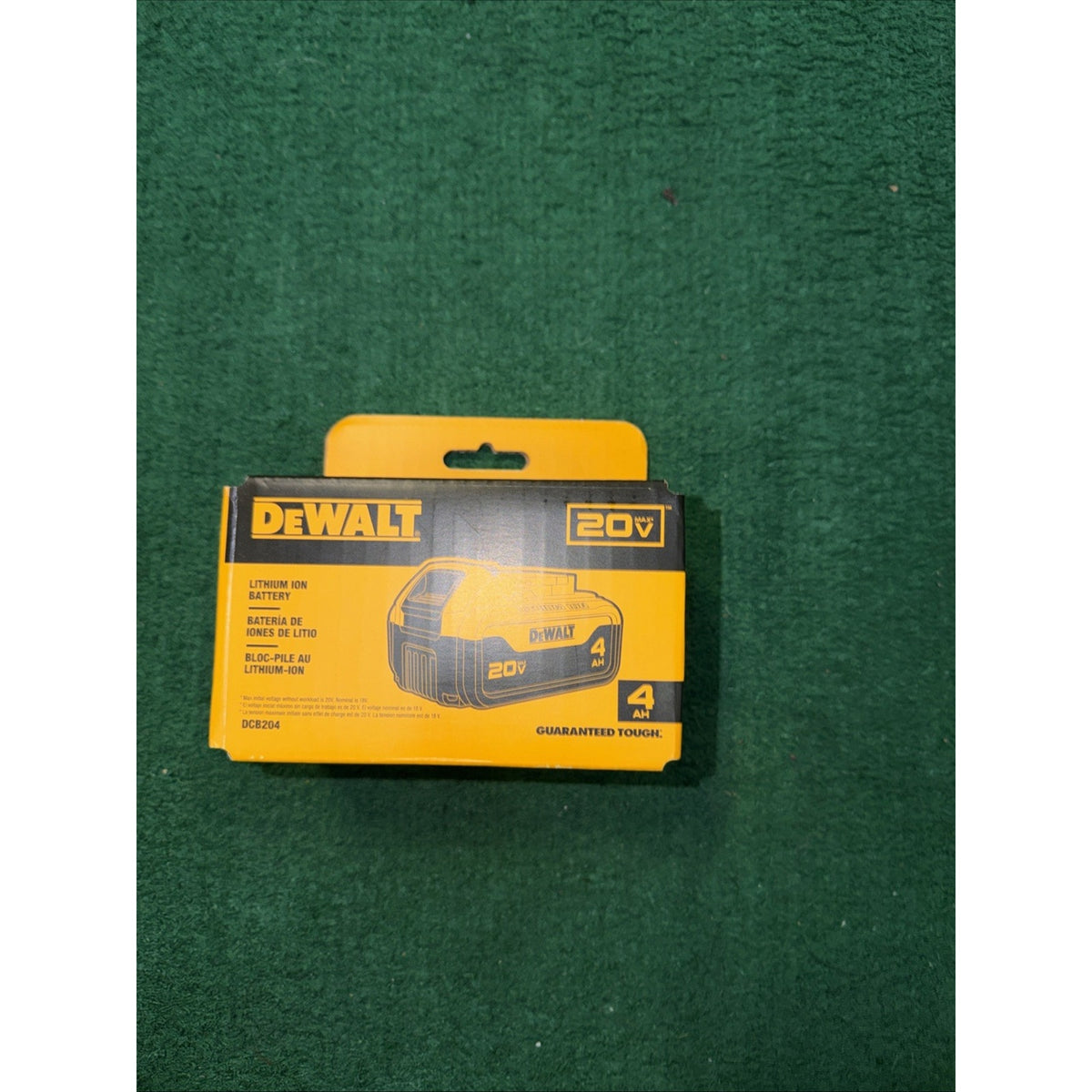 Boxed DeWalt 20V lithium-ion battery with 4Ah capacity, featuring yellow and black packaging, placed on a green textured surface.