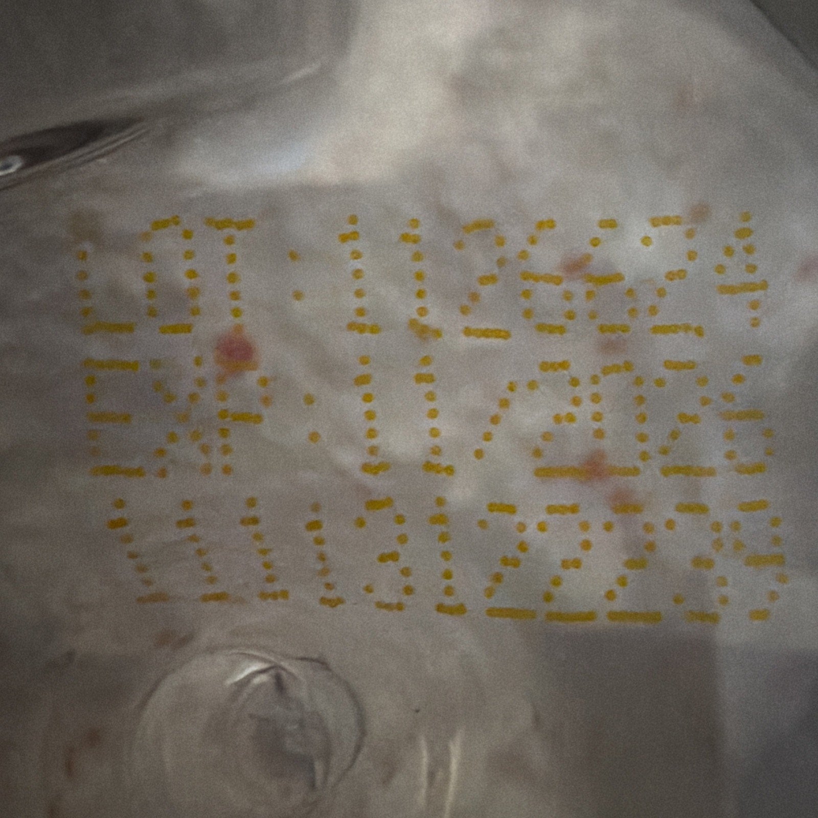 Close-up of yellow dotted lot number "1126274" and expiration date "11/2026" printed on a reflective, crinkled silver surface.