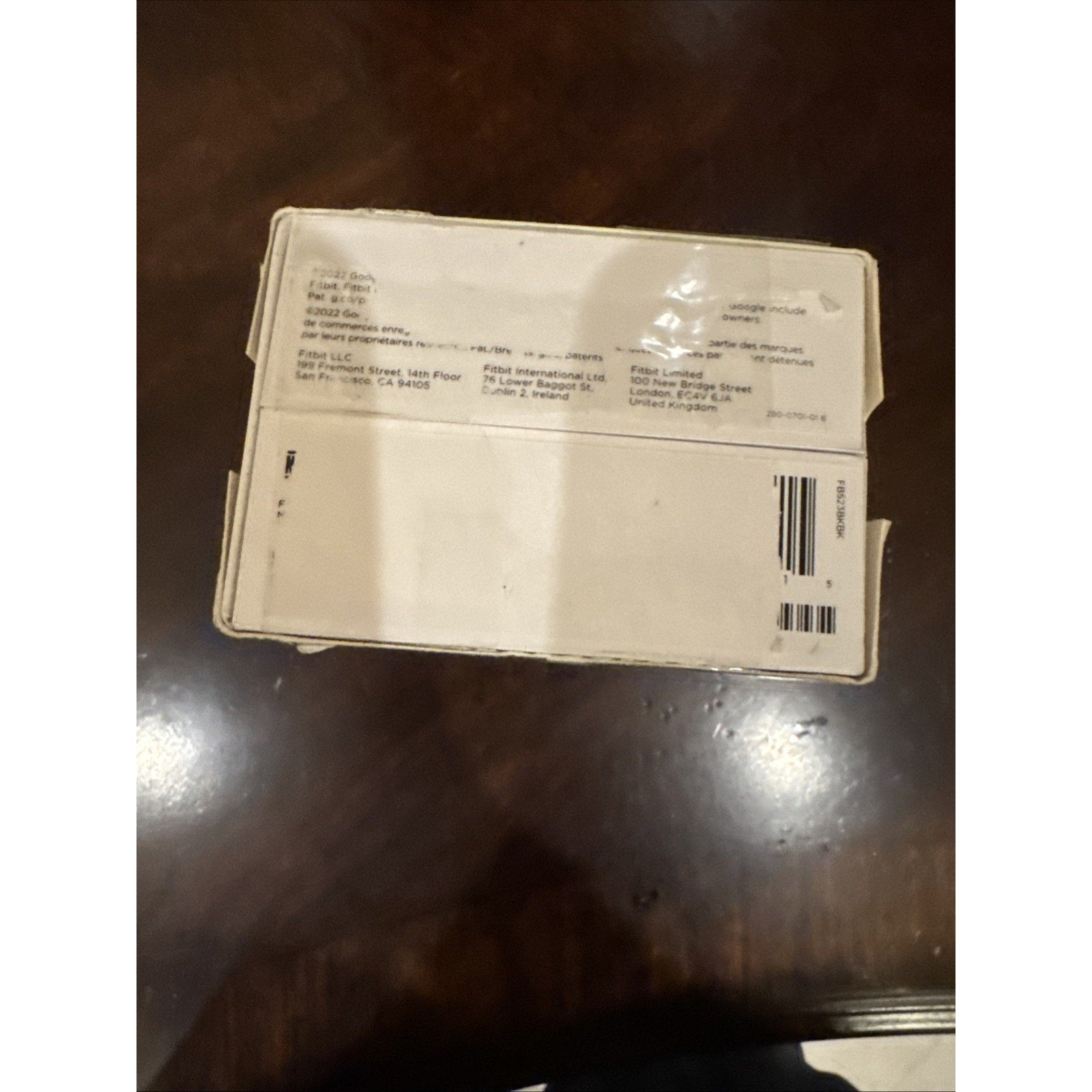 Box packaging of Fitbit Versa 4 Fitness Smartwatch in black showing shipping labels and barcode on white background