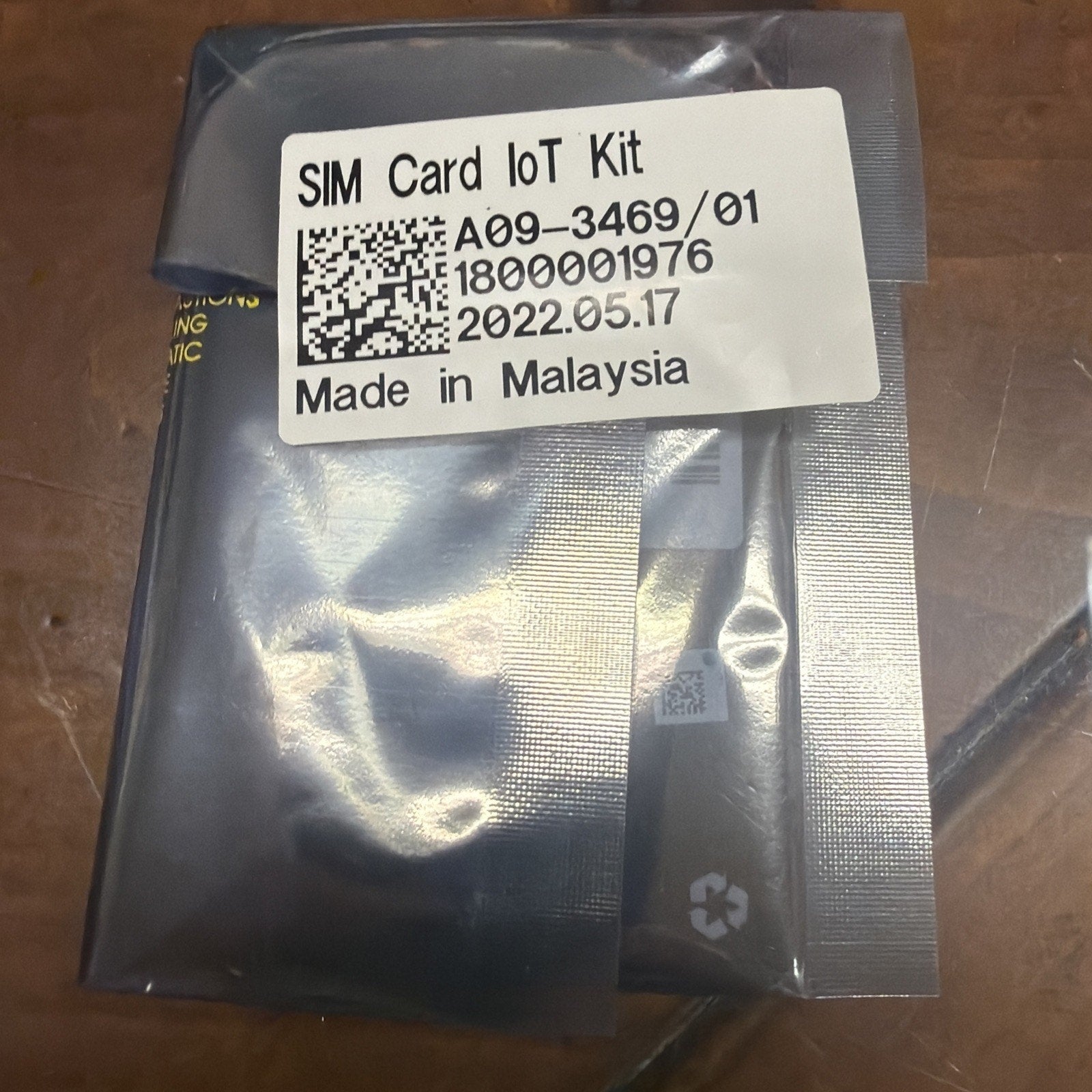Sealed gray anti-static plastic package containing a SIM Card IoT Kit with a white label showing product code, batch number, manufacturing date, and "Made in Malaysia" text.