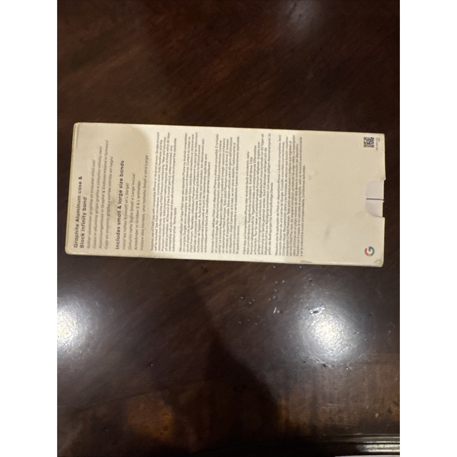 Google Fitbit Versa 4 Fitness Smartwatch box back with product information text on wooden surface background