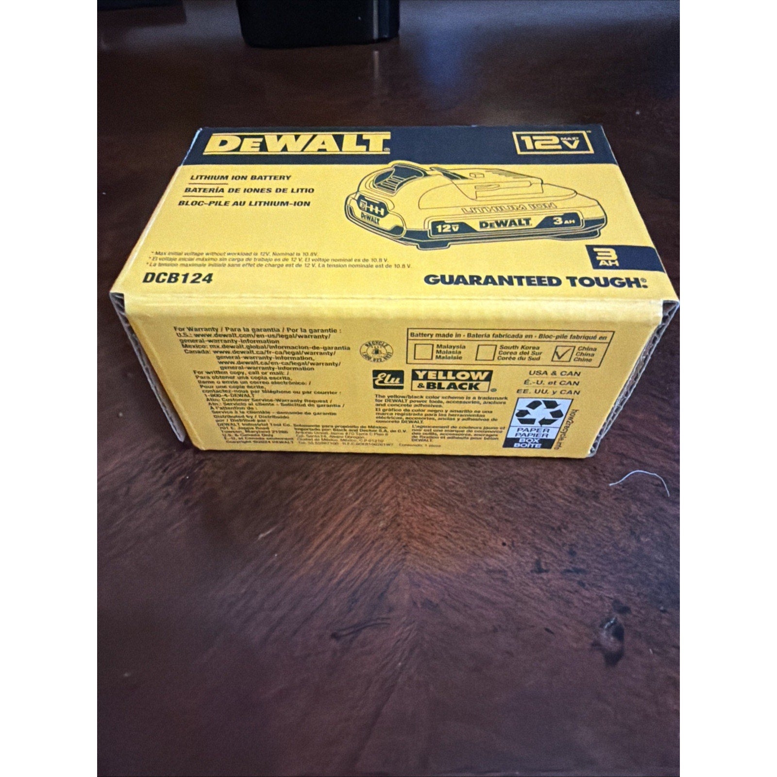 Yellow and black DeWalt packaging box for a 12V lithium-ion battery with a 3Ah capacity, featuring product branding, model number DCB124, and warranty details printed on the surface.