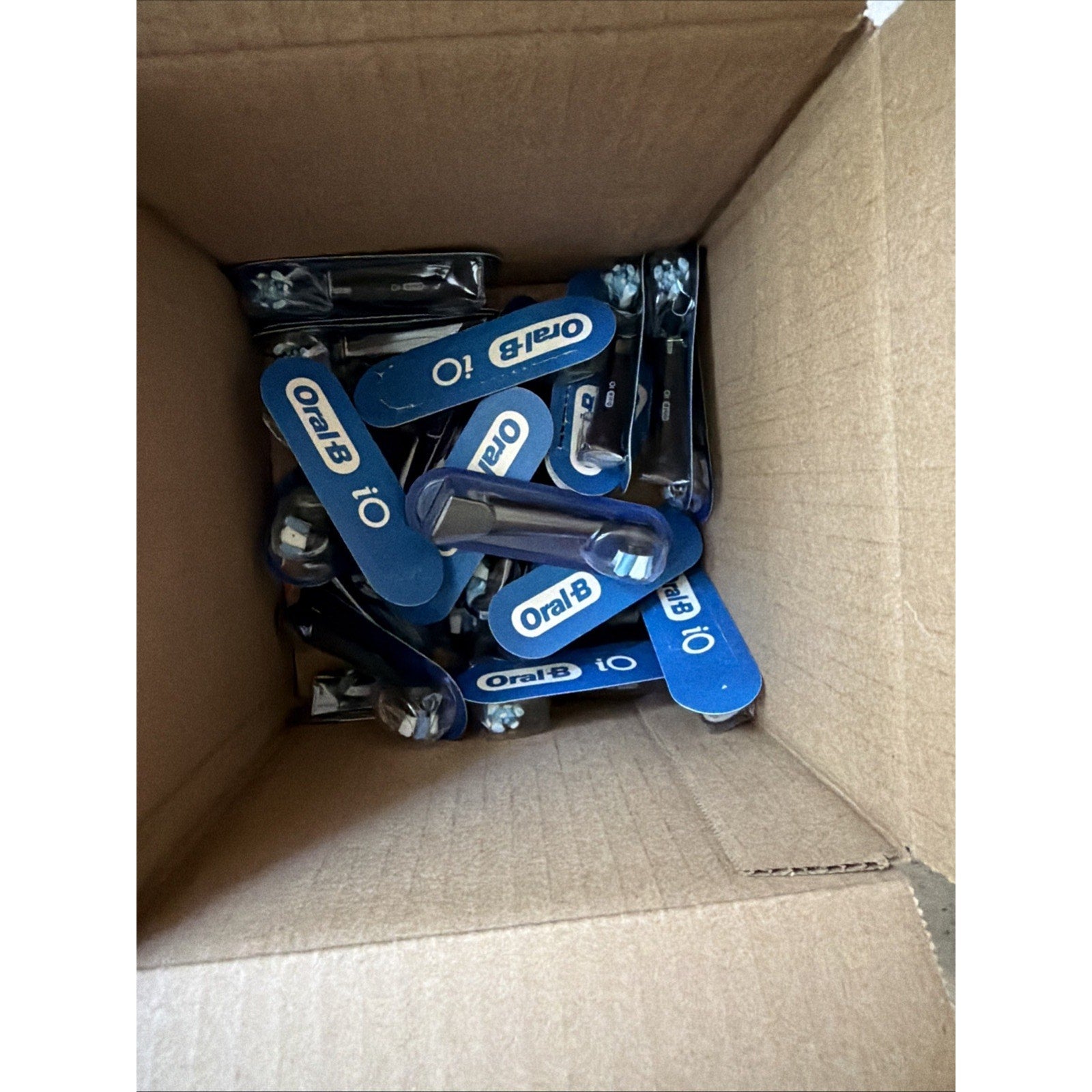 Box filled with multiple Oral-B iO Series Ultimate Clean replacement brush heads in black packaging inside cardboard box