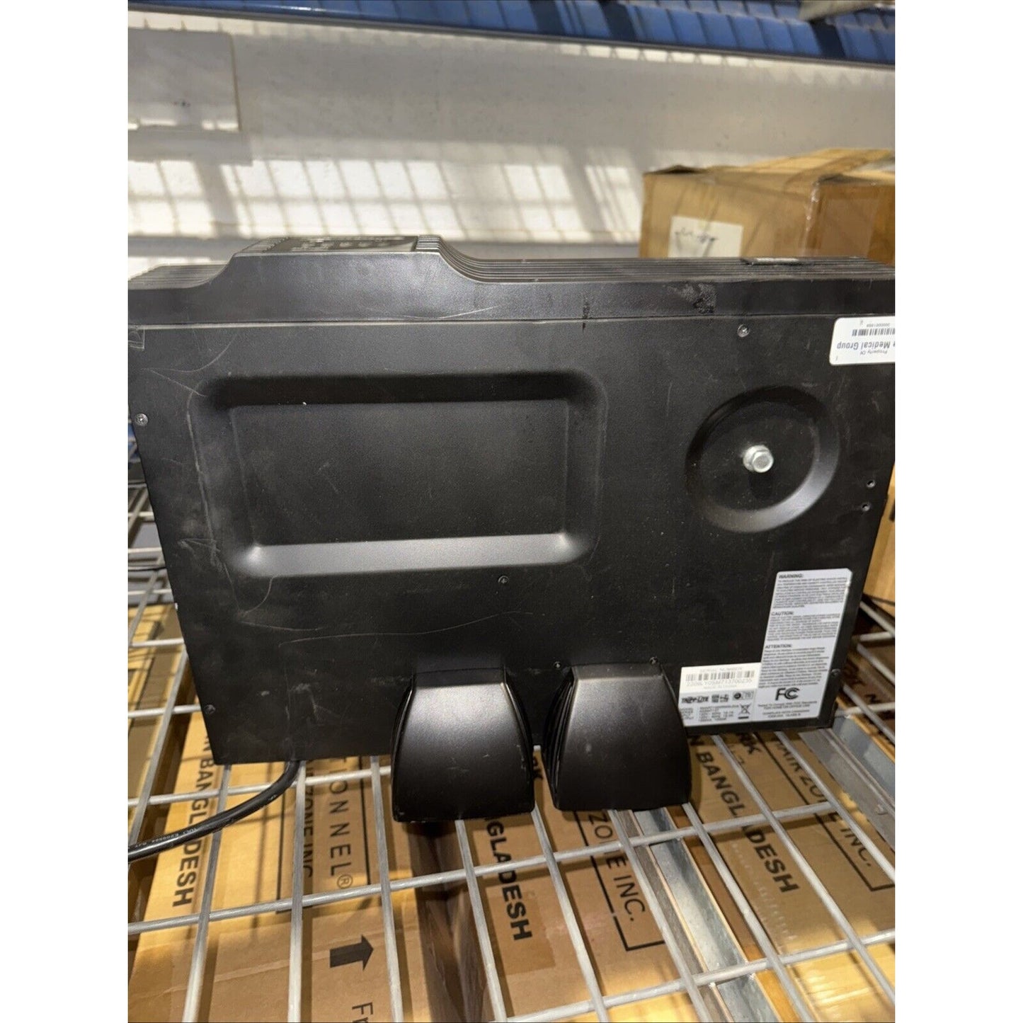 Tripp Lite SU1500RTXL2UA Smart Online UPS black unit with six power outlets on metal rack in warehouse setting