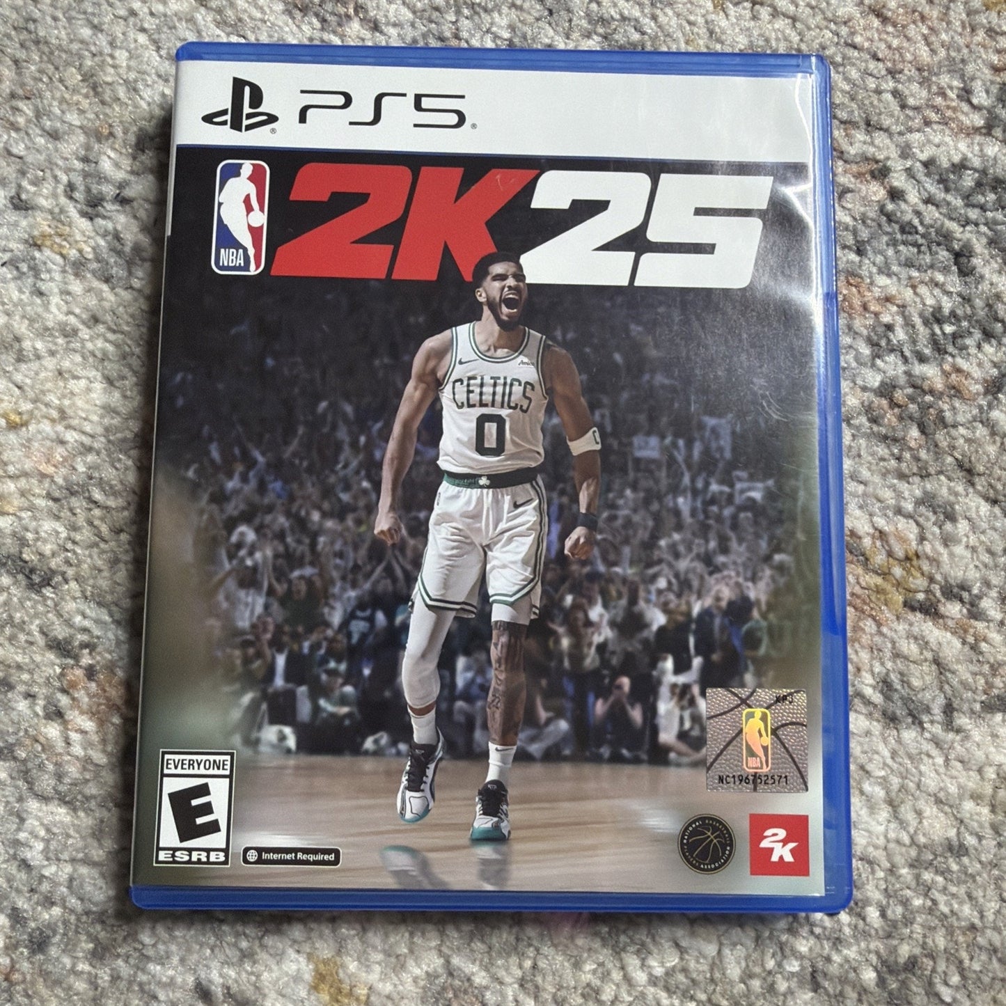 PlayStation 5 game case for NBA 2K25 featuring a basketball player in a Celtics uniform celebrating on the court with a crowd in the background and rating information on the front.