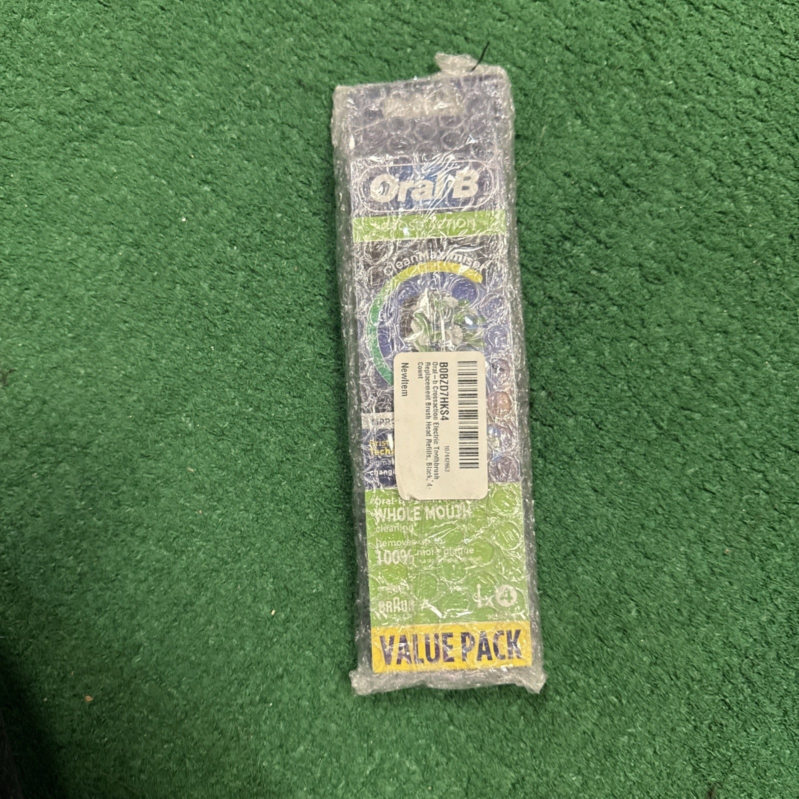 Oral B Cross Action Brush Heads 4-pack in retail packaging wrapped in protective bubble wrap on green surface
