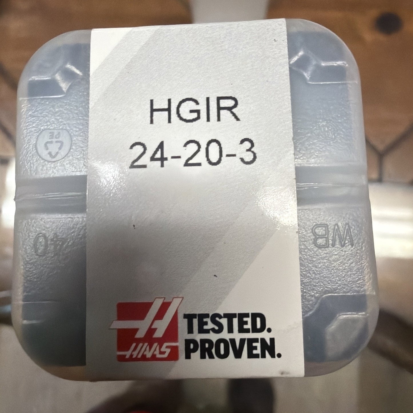 Transparent plastic container with a white label showing the text “HGIR 24-20-3” and a red logo with the words “TESTED. PROVEN.” on a wooden surface background.