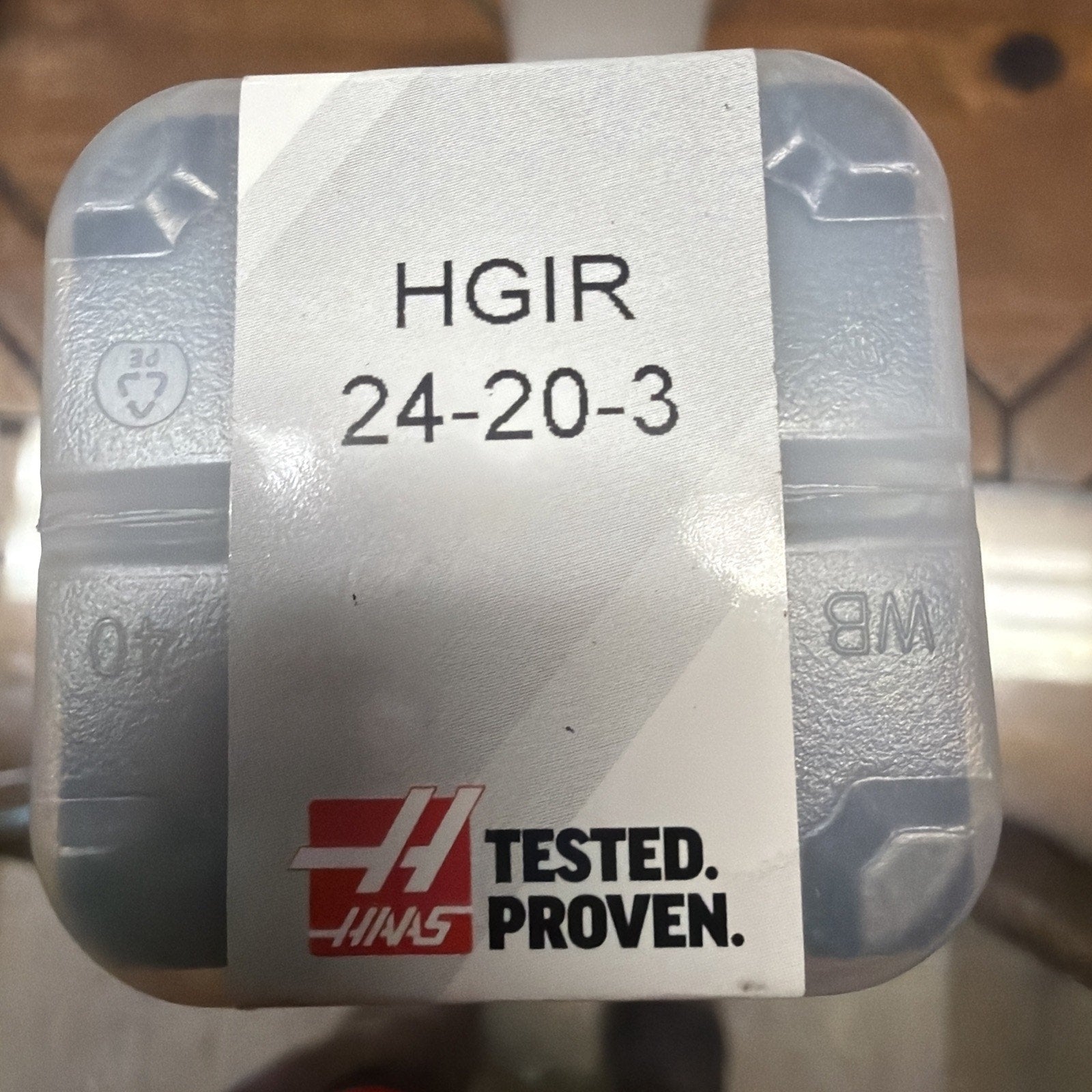 Transparent plastic container with a white label showing the text “HGIR 24-20-3” and a red logo with the words “TESTED. PROVEN.” on a wooden surface background.