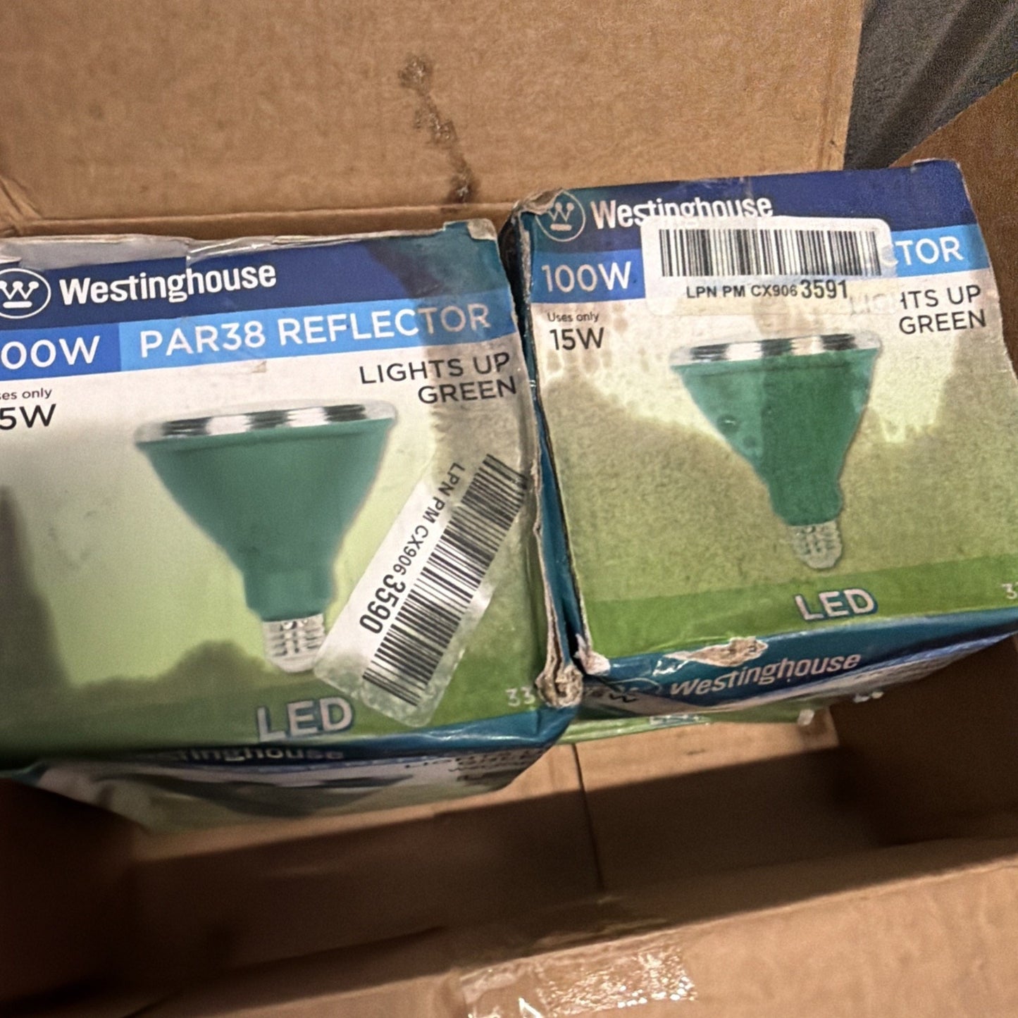 Two Westinghouse 100W PAR38 Reflector LED light bulbs in blue and white retail boxes inside a cardboard shipping box, with visible barcodes and product information.