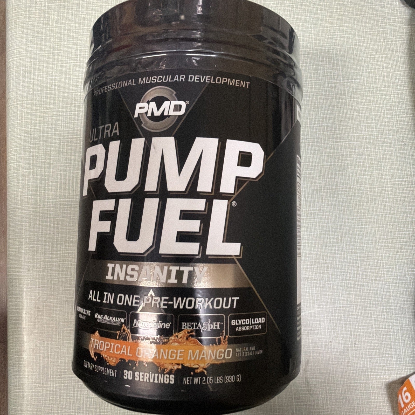 Black container of PMD Ultra Pump Fuel Insanity pre-workout supplement in tropical orange mango flavor, with 30 servings and nutritional highlights displayed on the label.