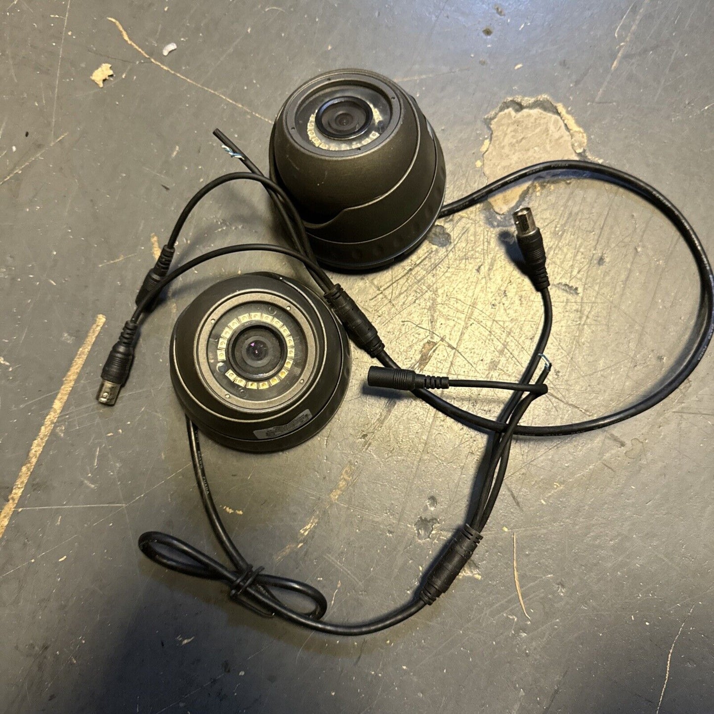 Two black 720p/960 dome security cameras with cables on dark floor showing lens and infrared LEDs ring