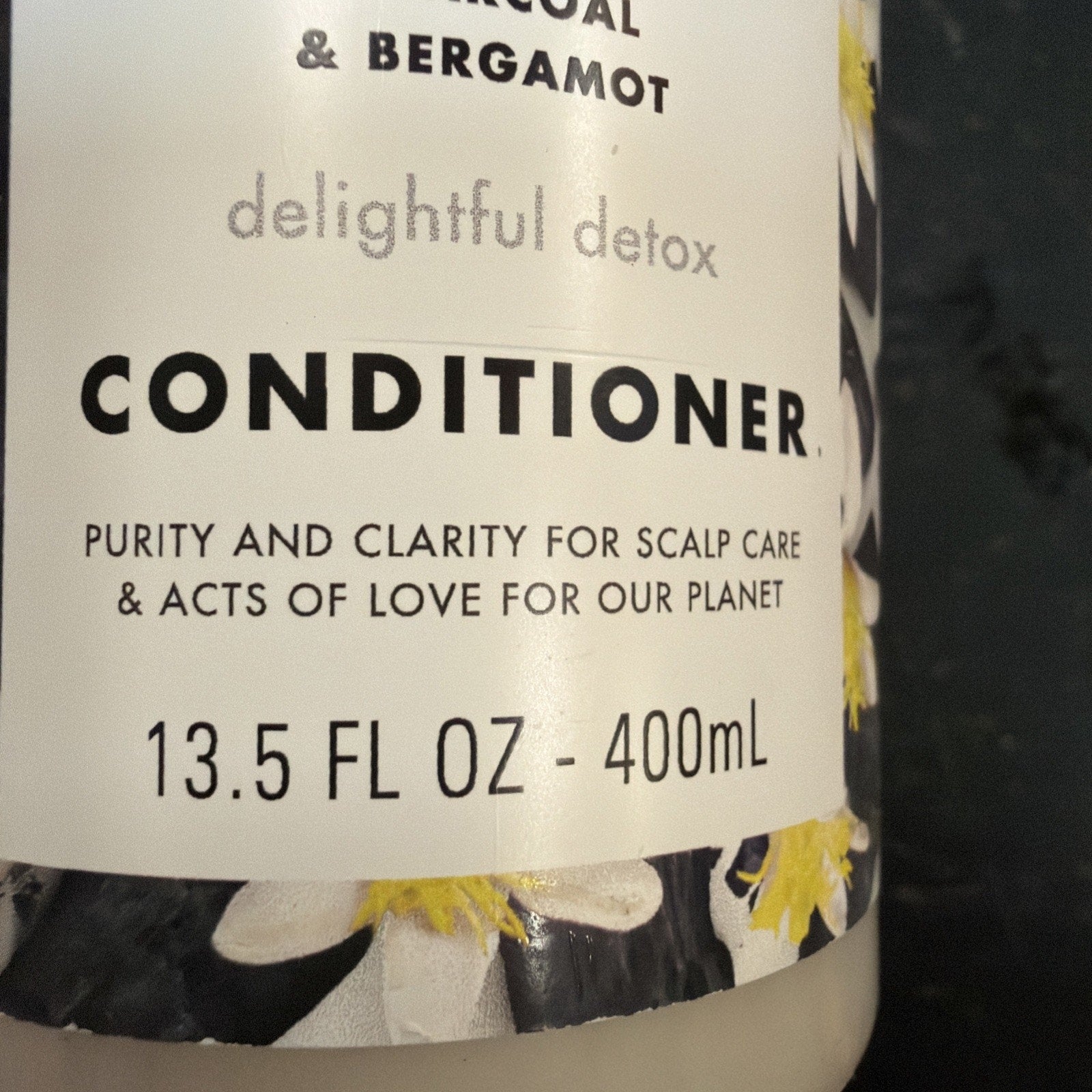 Close-up of a conditioner bottle label highlighting charcoal and bergamot scent, featuring text about scalp care, environmental love, and the 13.5 fl oz (400 mL) volume.