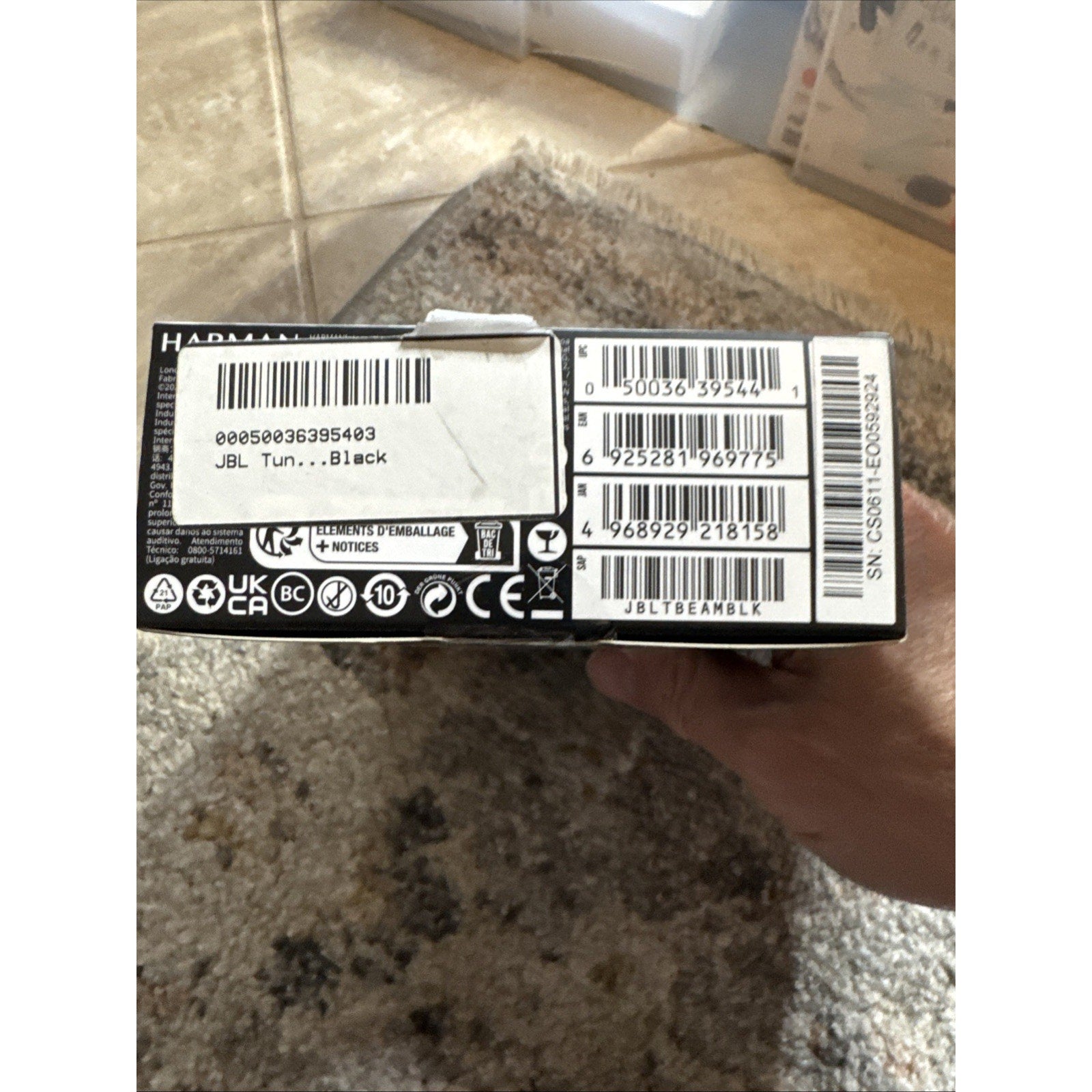 Bottom view of JBL by Harman Tune Beam earbuds black packaging box showing barcodes and labels