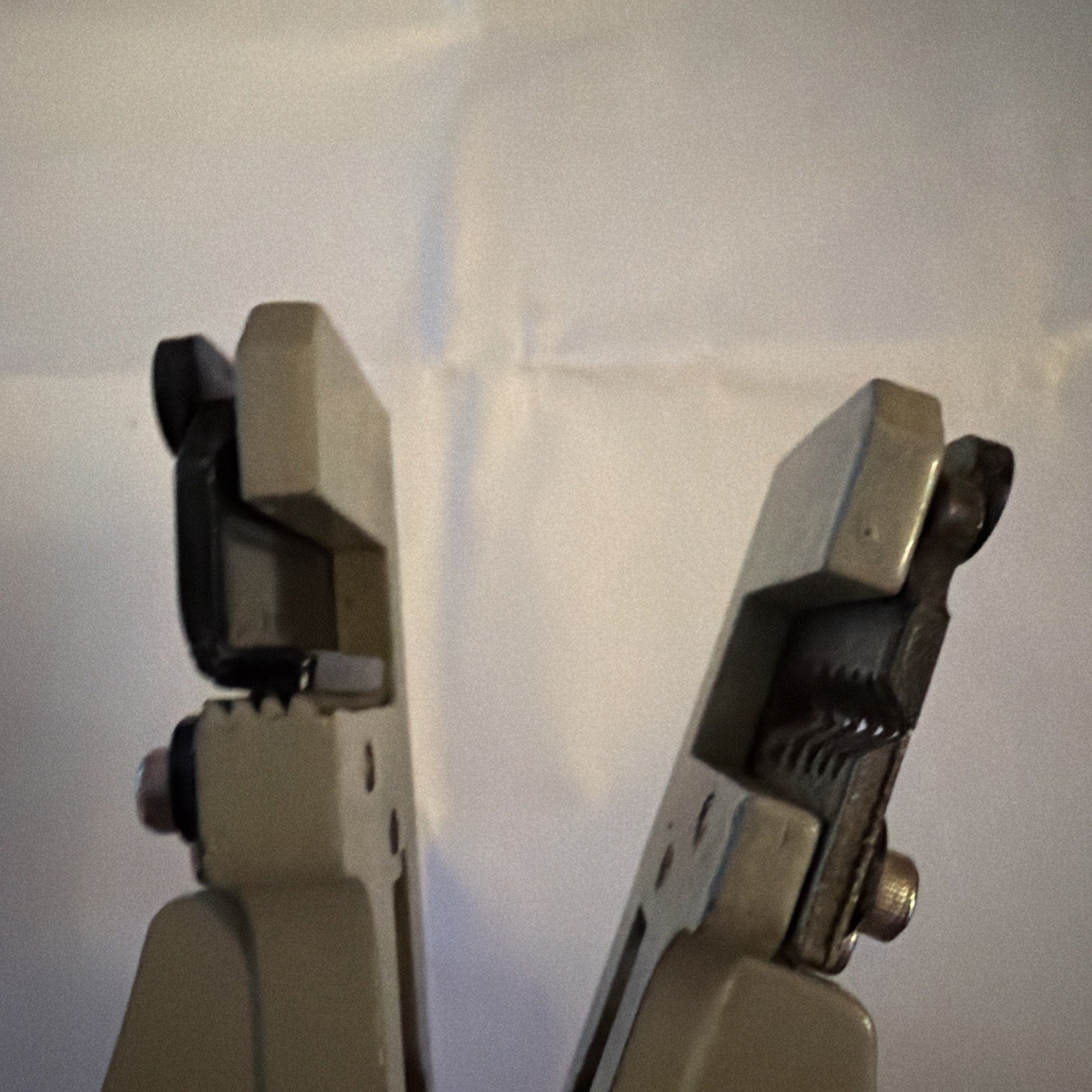 Close-up of metal jaws on Electrical Wire Stripper Tool Type B with grey handles against plain background