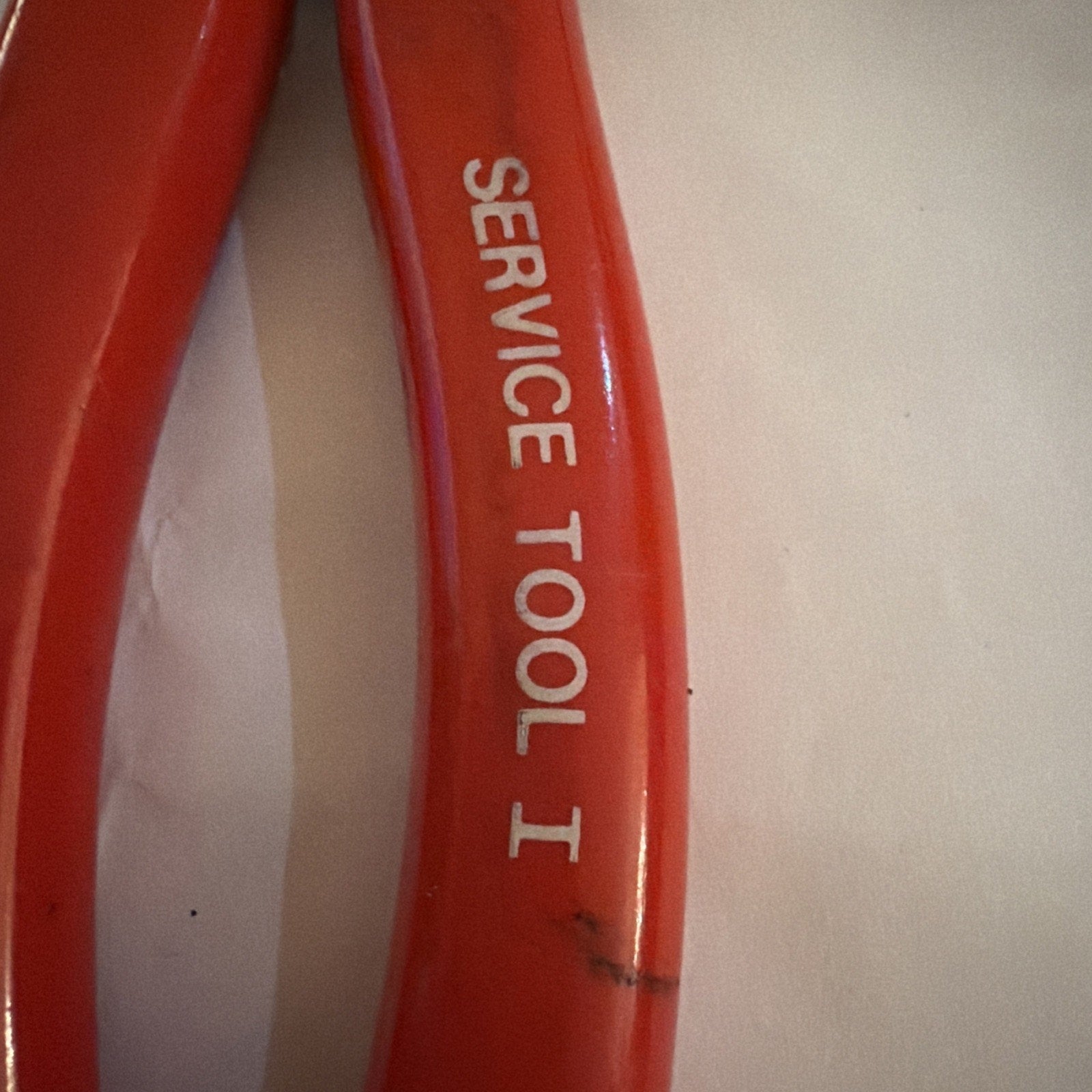 Close-up of red vintage AMP Service Tool I crimper handle with white text showing 