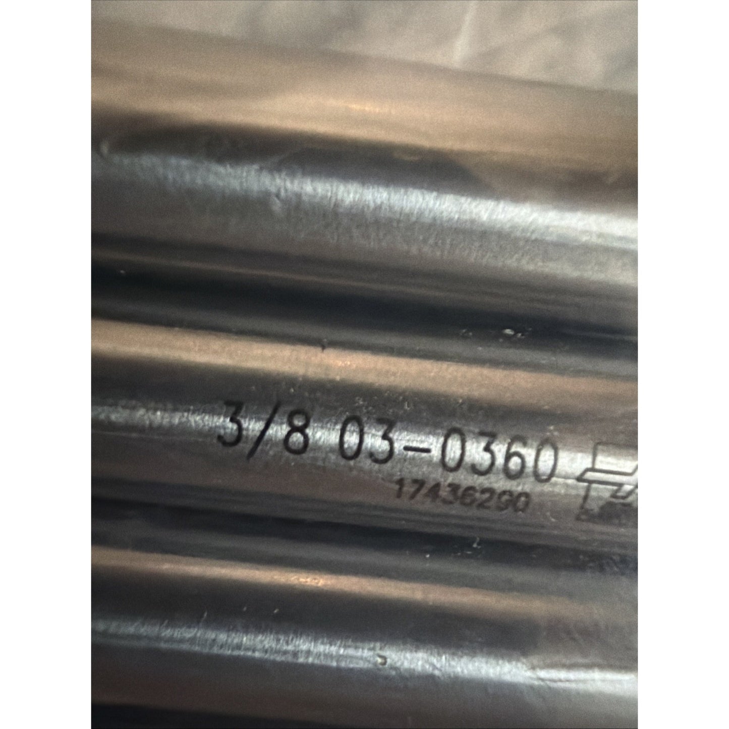 Close-up of several smooth metal rods with engraved numerical codes and markings, reflecting light on their polished surfaces, arranged horizontally.