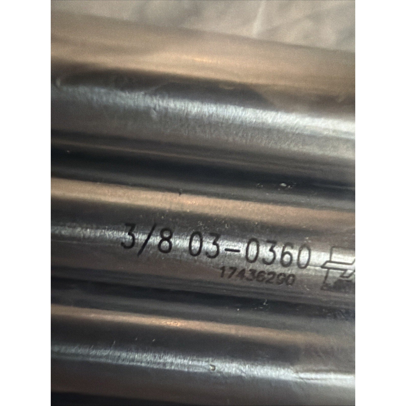 Close-up of several smooth metal rods with engraved numerical codes and markings, reflecting light on their polished surfaces, arranged horizontally.