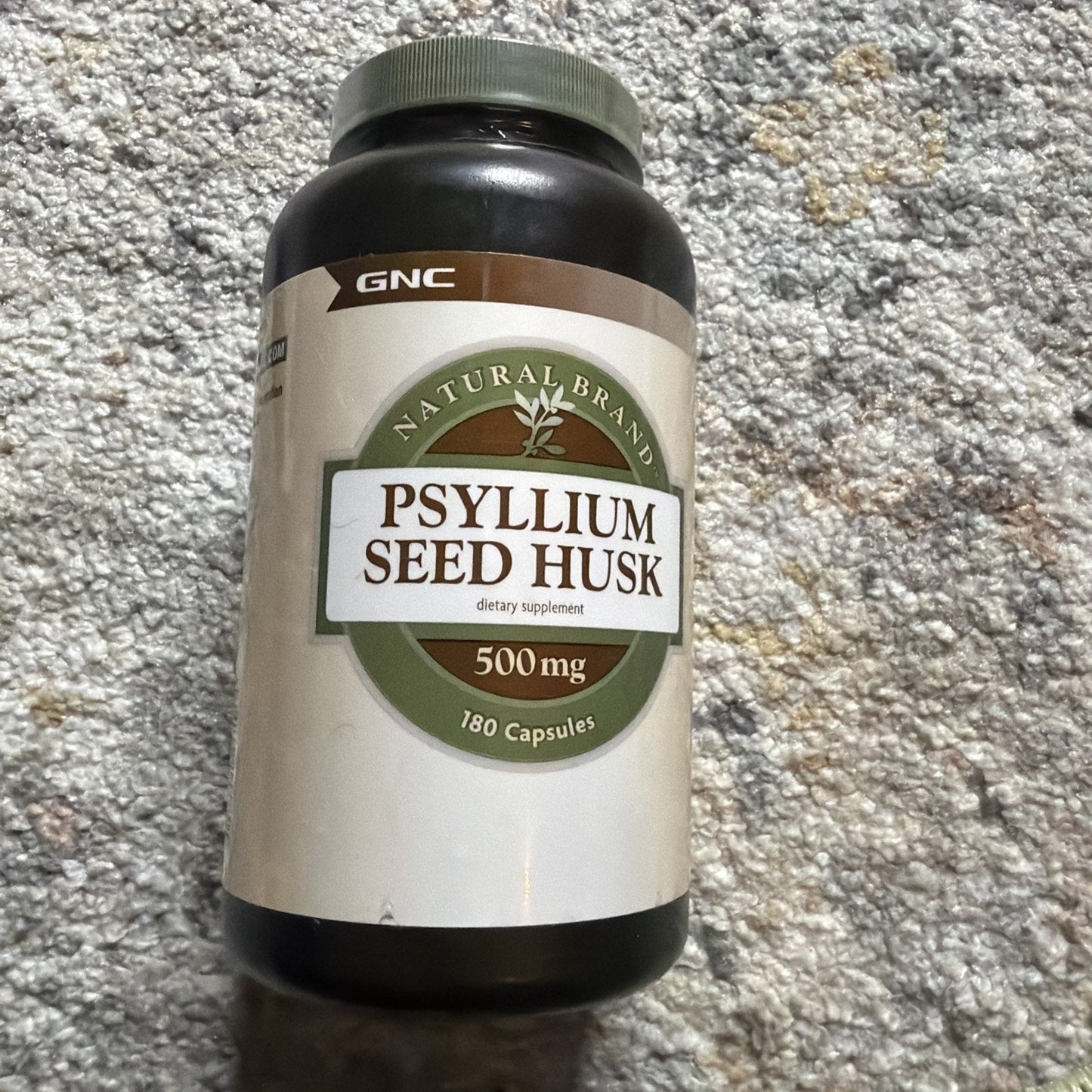 Dark brown plastic bottle of psyllium seed husk dietary supplement with 500 mg capsules, labeled as a natural brand, containing 180 capsules.