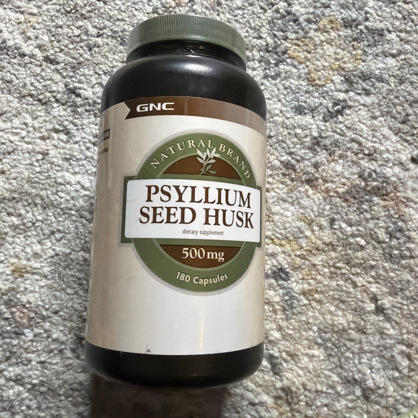 Dark brown plastic bottle of psyllium seed husk dietary supplement with 500 mg capsules, labeled as a natural brand, containing 180 capsules.