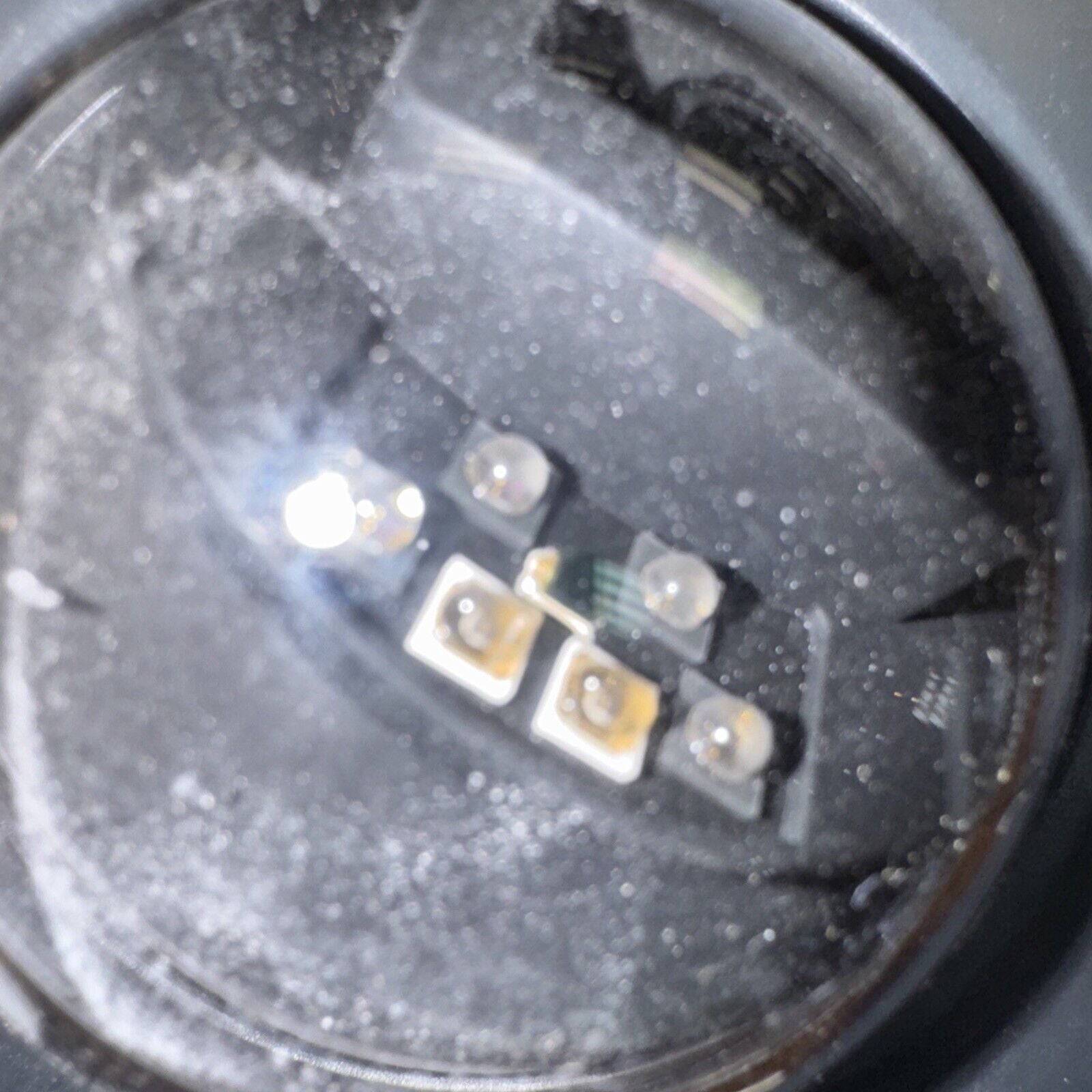 Close-up of Alarm.com infrared camera sensor and LED lights inside circular camera housing with dusty lens cover