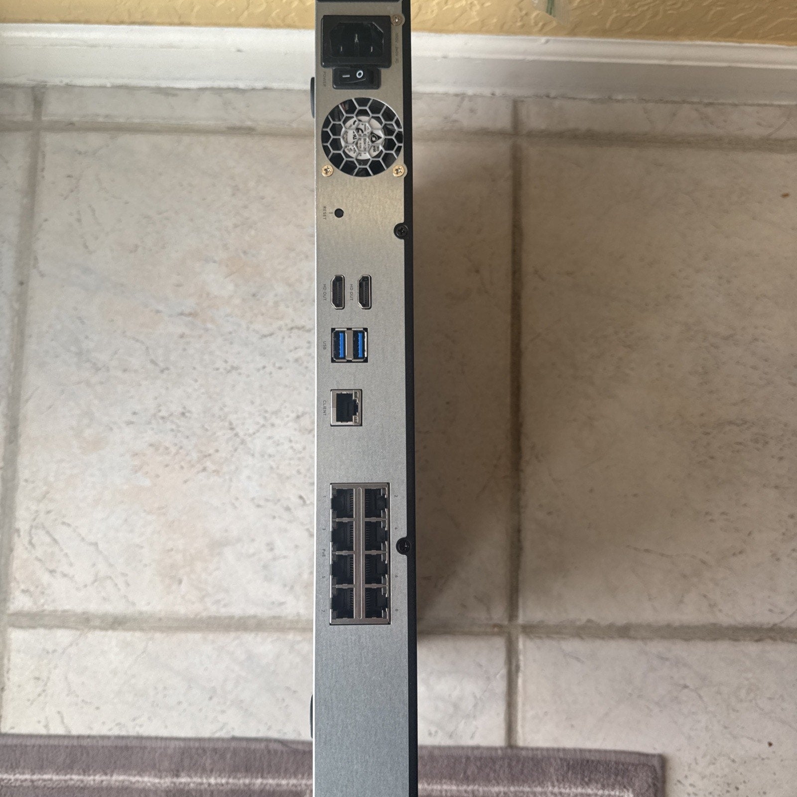 Rear view of Alarm.com 8CH Commercial Streaming Video Recorder showing ports and power supply unit on tiled floor background