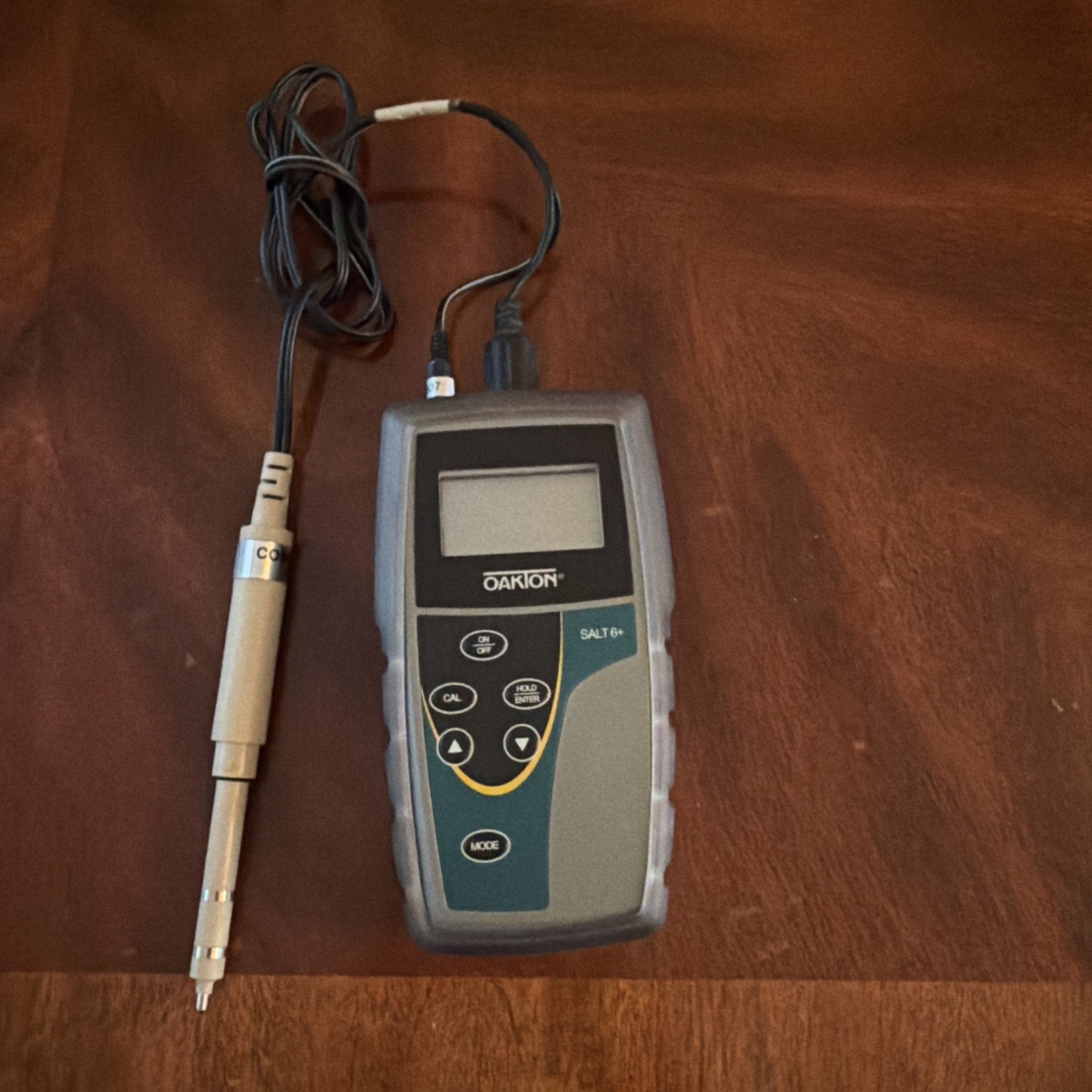 Oakton SALT 6+ Handheld Salinity Meter with probe showing buttons and LCD screen on wooden surface
