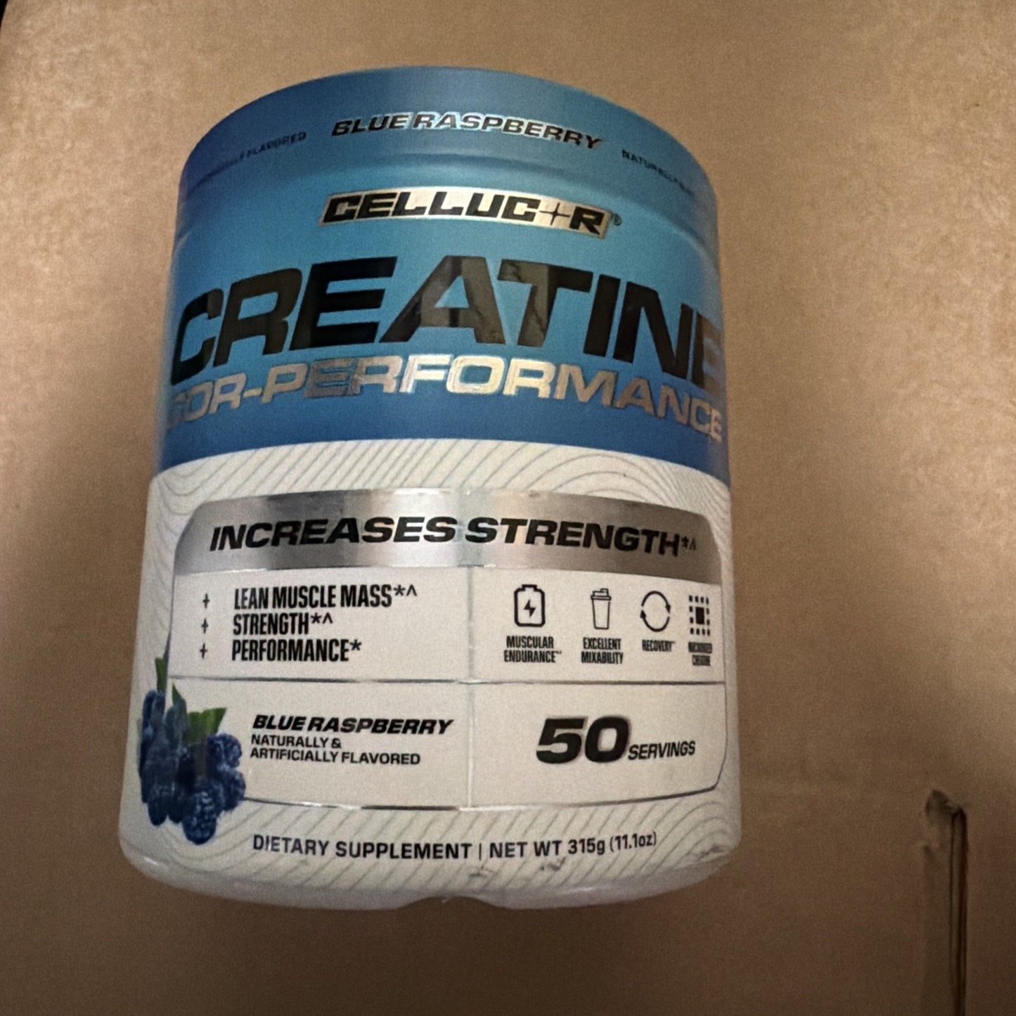 Blue and white container of Cellucor Creatine for Performance dietary supplement in blue raspberry flavor, highlighting increased strength, lean muscle mass, and 50 servings.