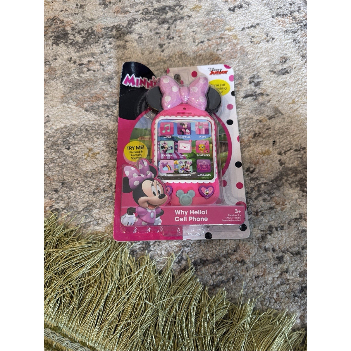 Children’s toy phone shaped like Minnie Mouse’s head with a pink bow, featuring interactive buttons and colorful icons, packaged in a pink and white polka dot backing card.