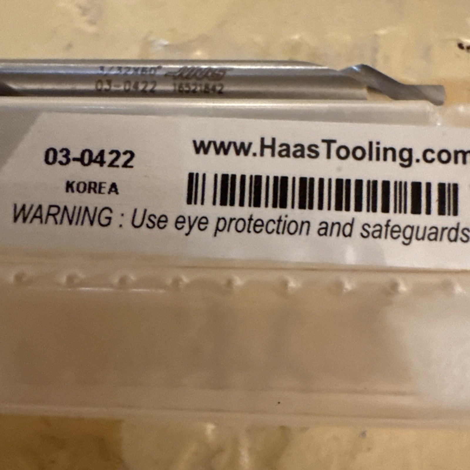 Clear plastic case label showing product code 03-0422, origin Korea, website URL, barcode, and a safety warning advising the use of eye protection and safeguards.