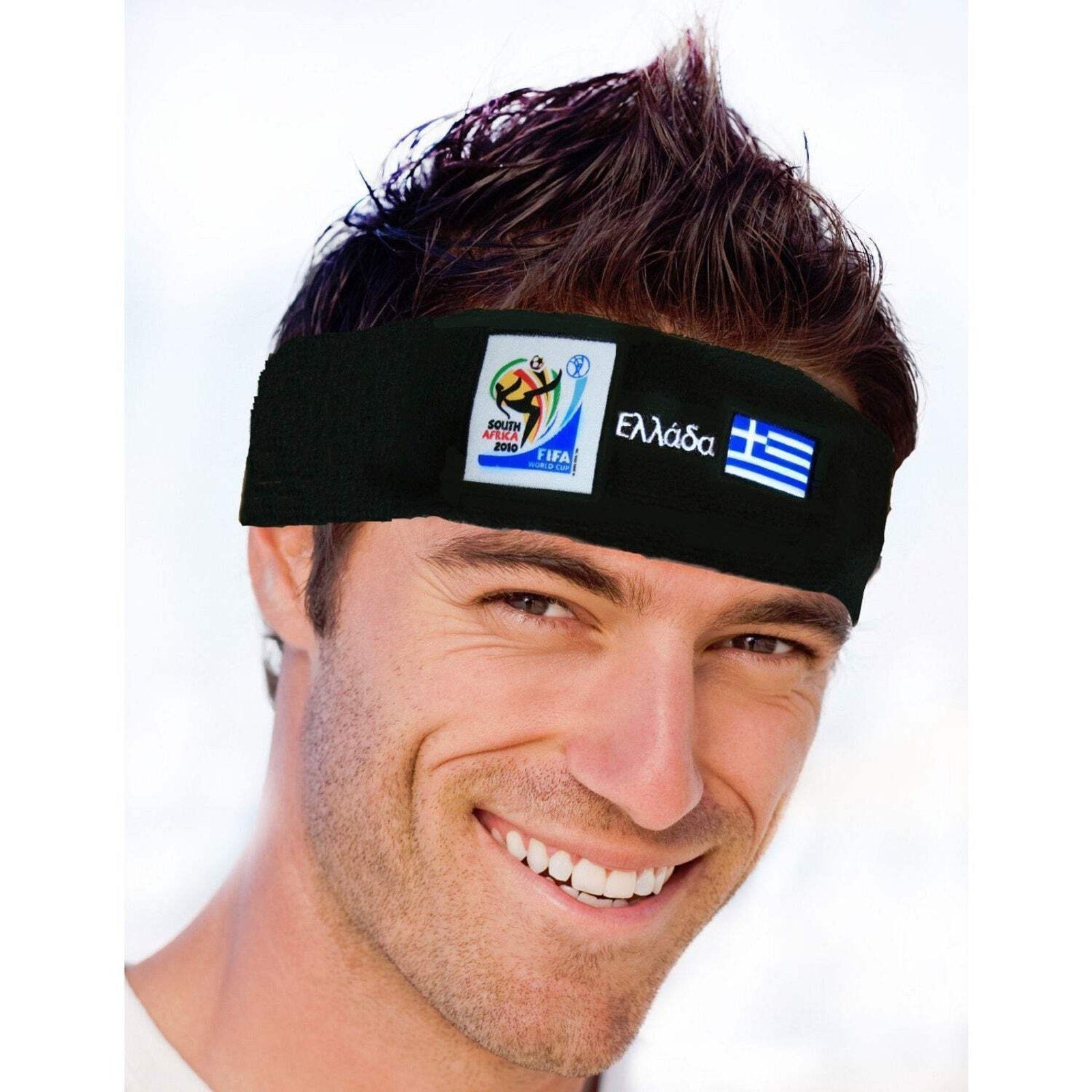 Man smiling and wearing a black headband featuring the 2010 FIFA World Cup South Africa logo, Greek text, and the blue and white flag of Greece on a white background.