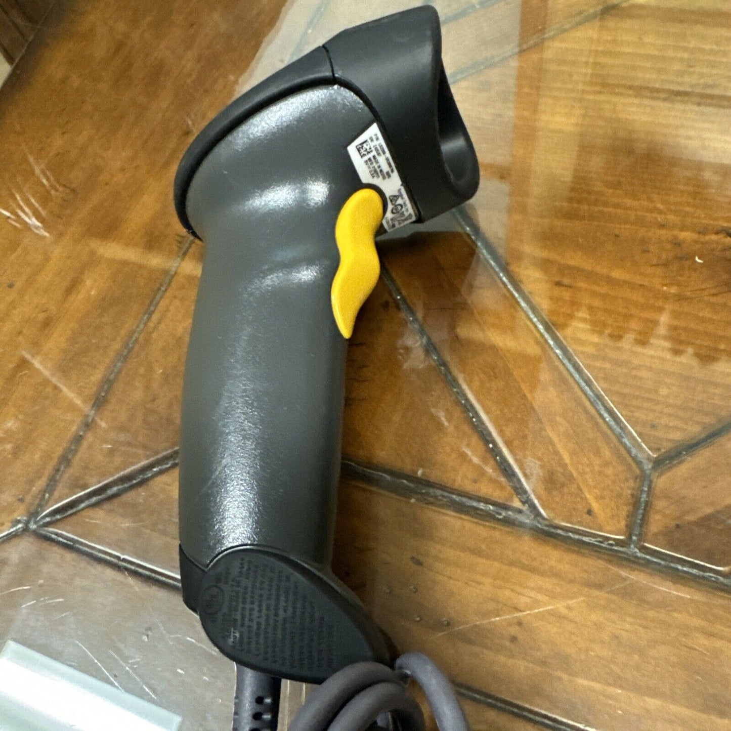 Symbol Motorola LS2208 handheld barcode scanner with yellow trigger and USB cord for point of sale use on wooden surface